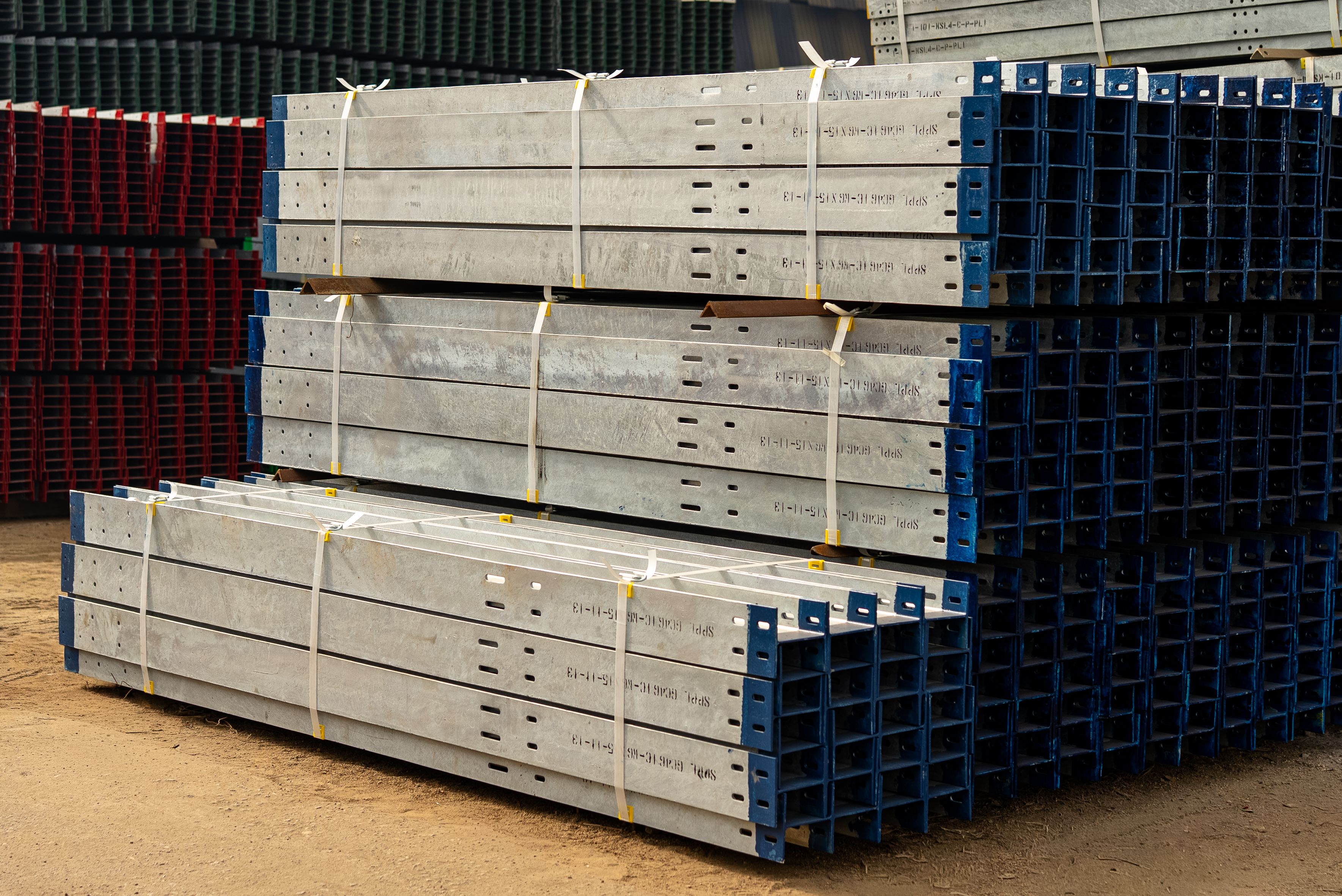 The picture describes stacks of prefabricated steel components stored in an industrial yard for use in construction projects.