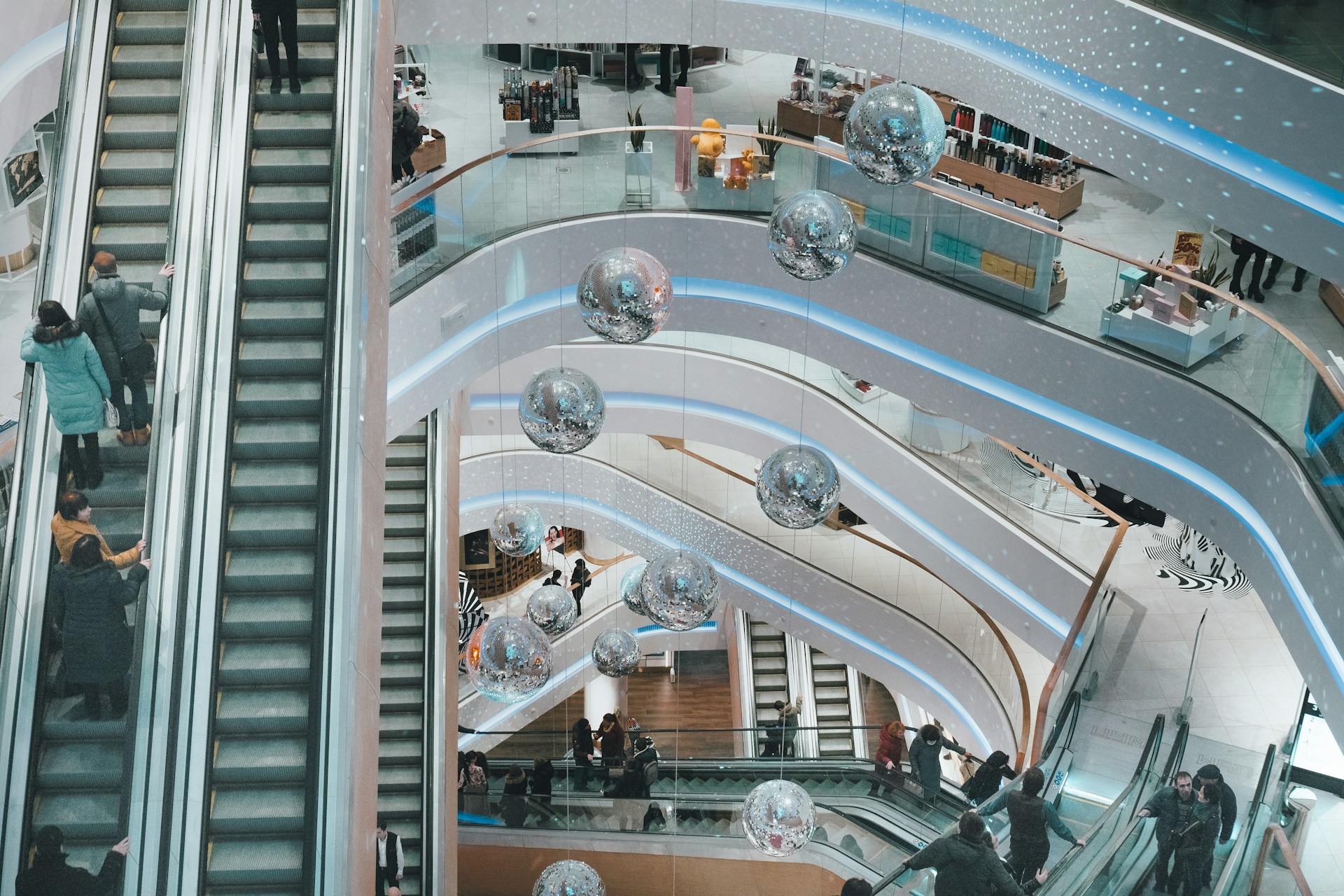 The photo presents people using escalators inside a shopping centre.