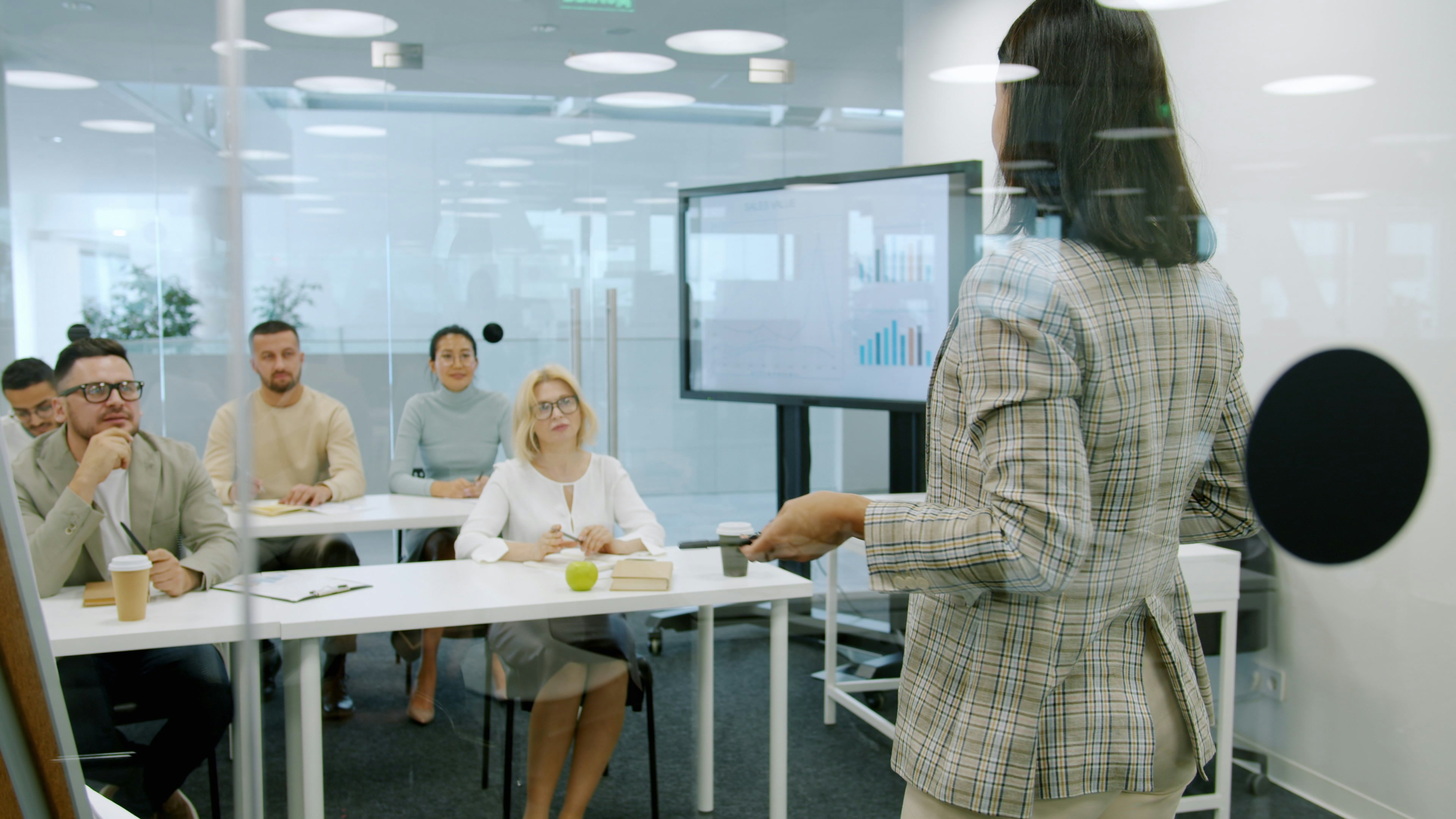 Woman presenting to an attentive audience in a modern office