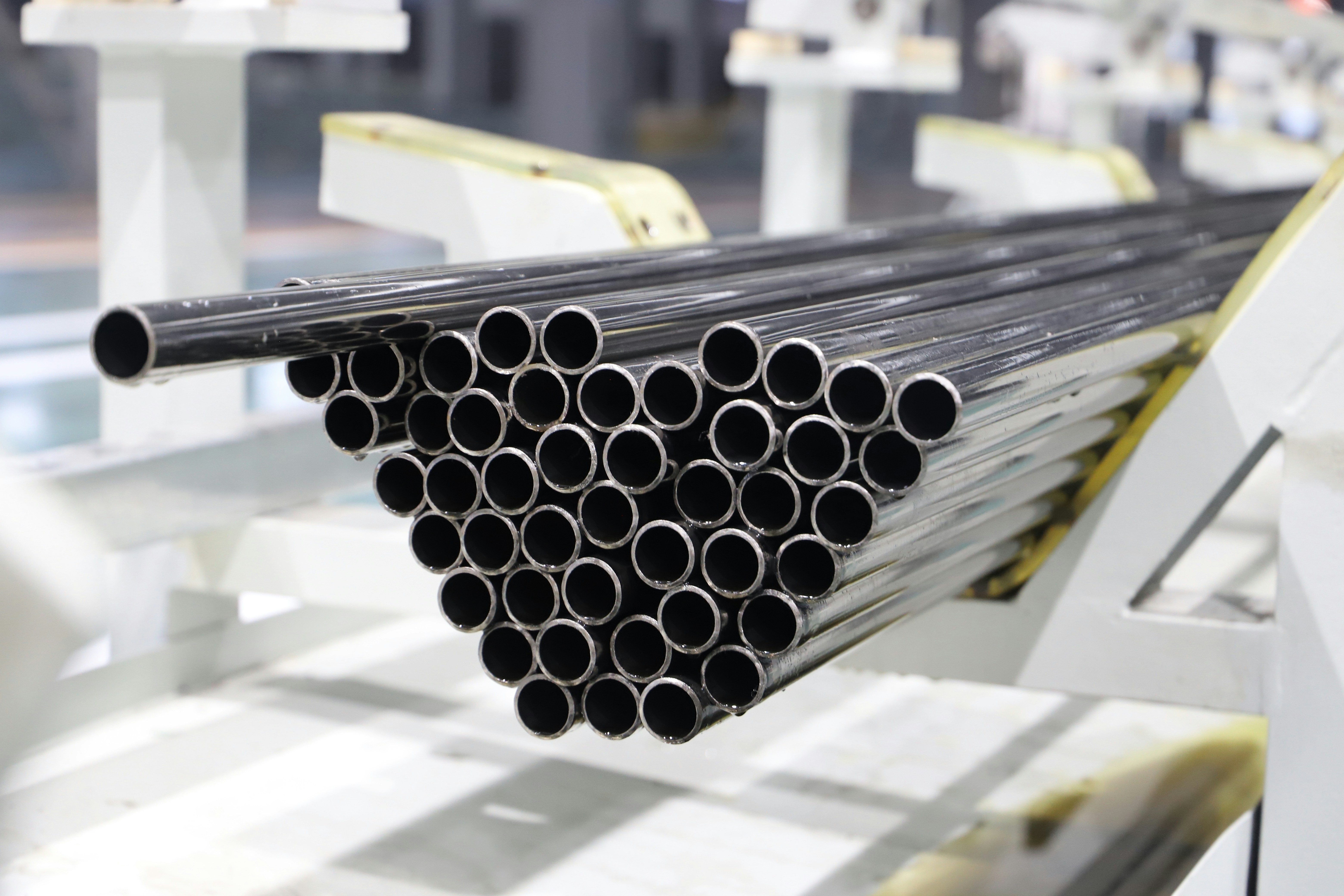 The picture describes a stack of metal pipes in an industrial manufacturing facility.