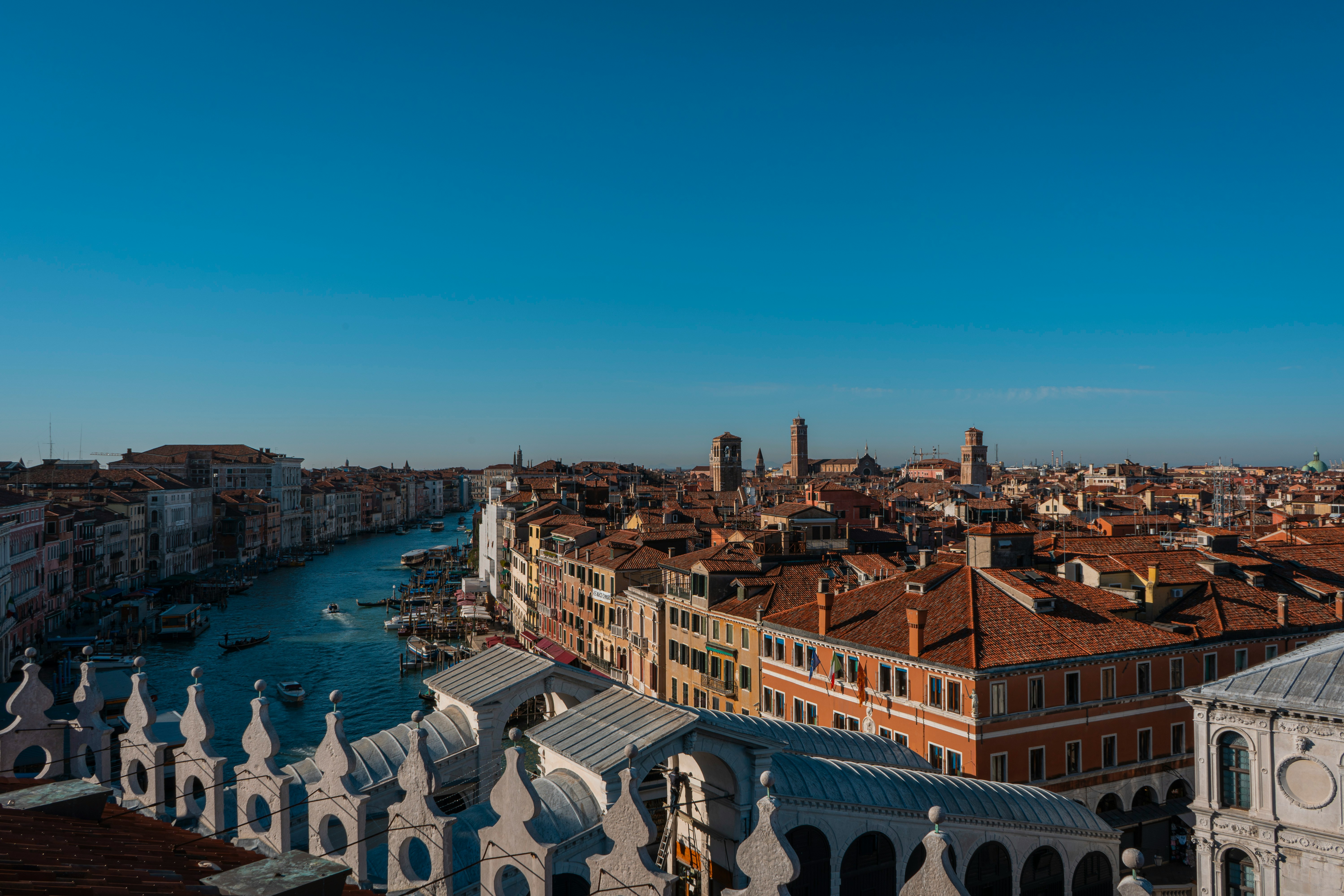 Aerial view of Venice, Italy, showing the Grand Canal winding between historic buildings and the Rialto Bridge. 