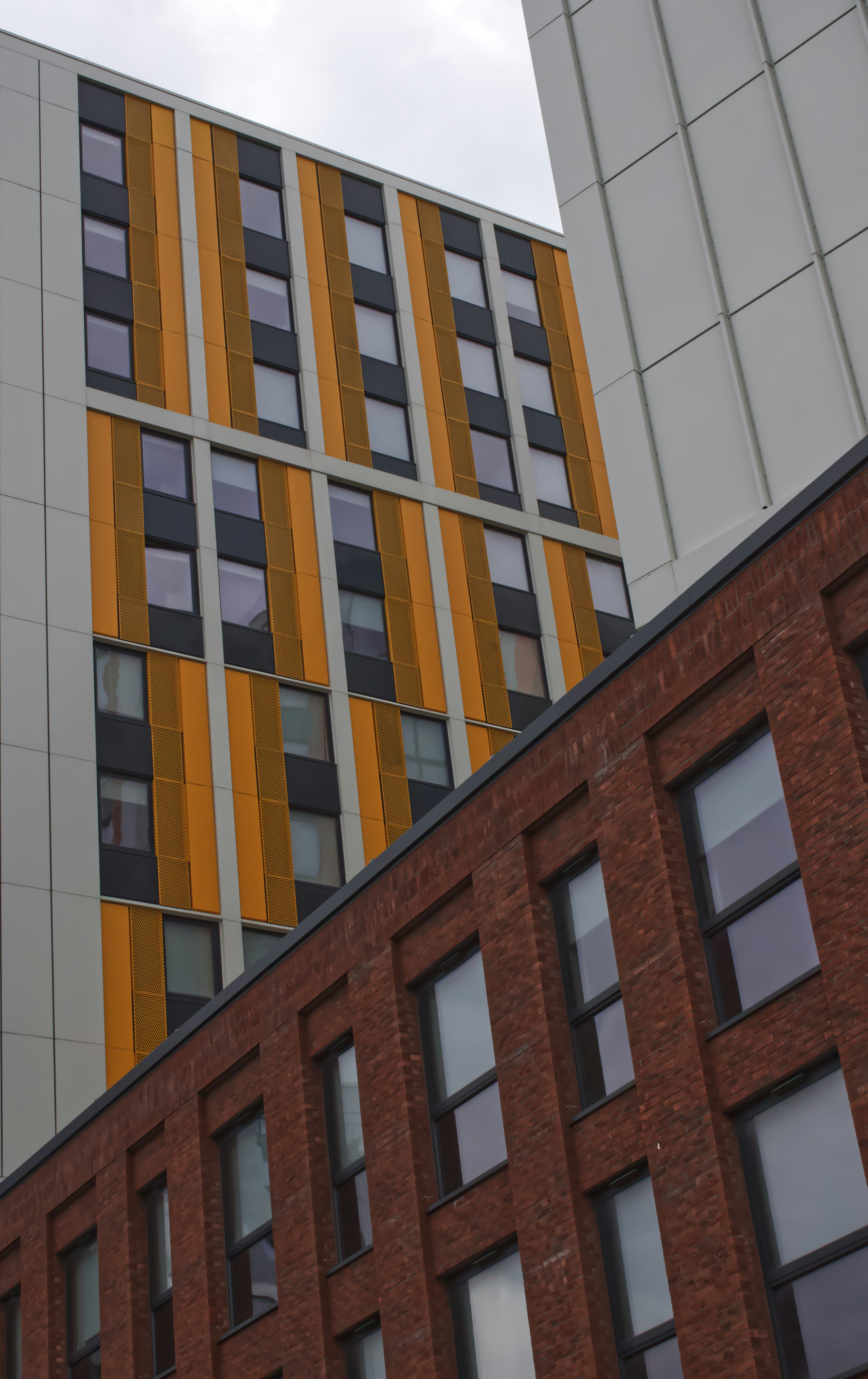 This picture shows a contemporary urban building complex viewed from below, highlighting the contrast between modern architectural styles and materials.