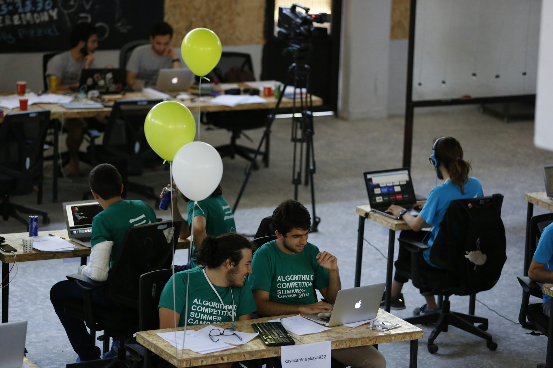 The photo presents participants working at a programming competition or hackathon.