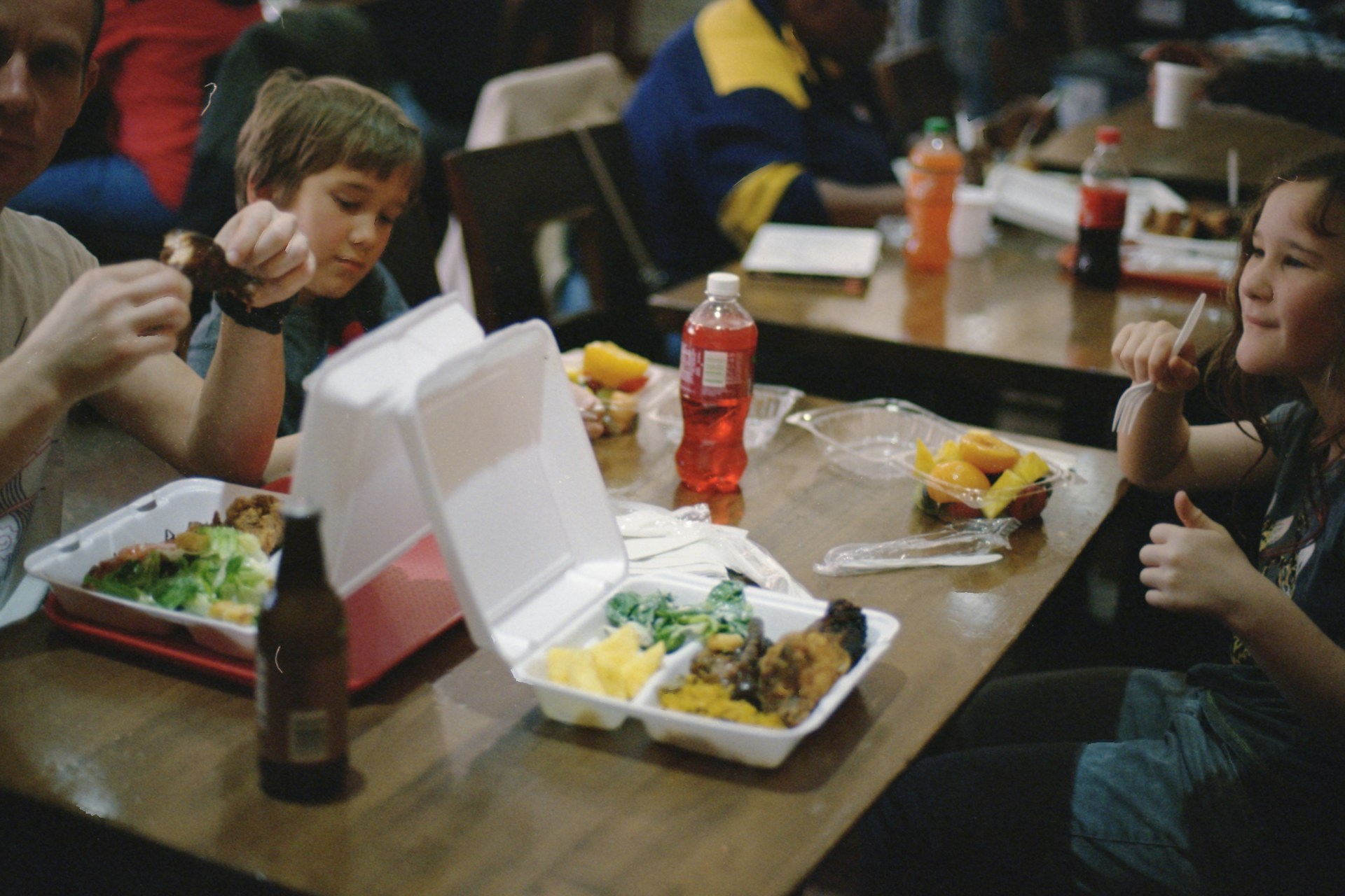 The photo presents people eating takeaway food together.