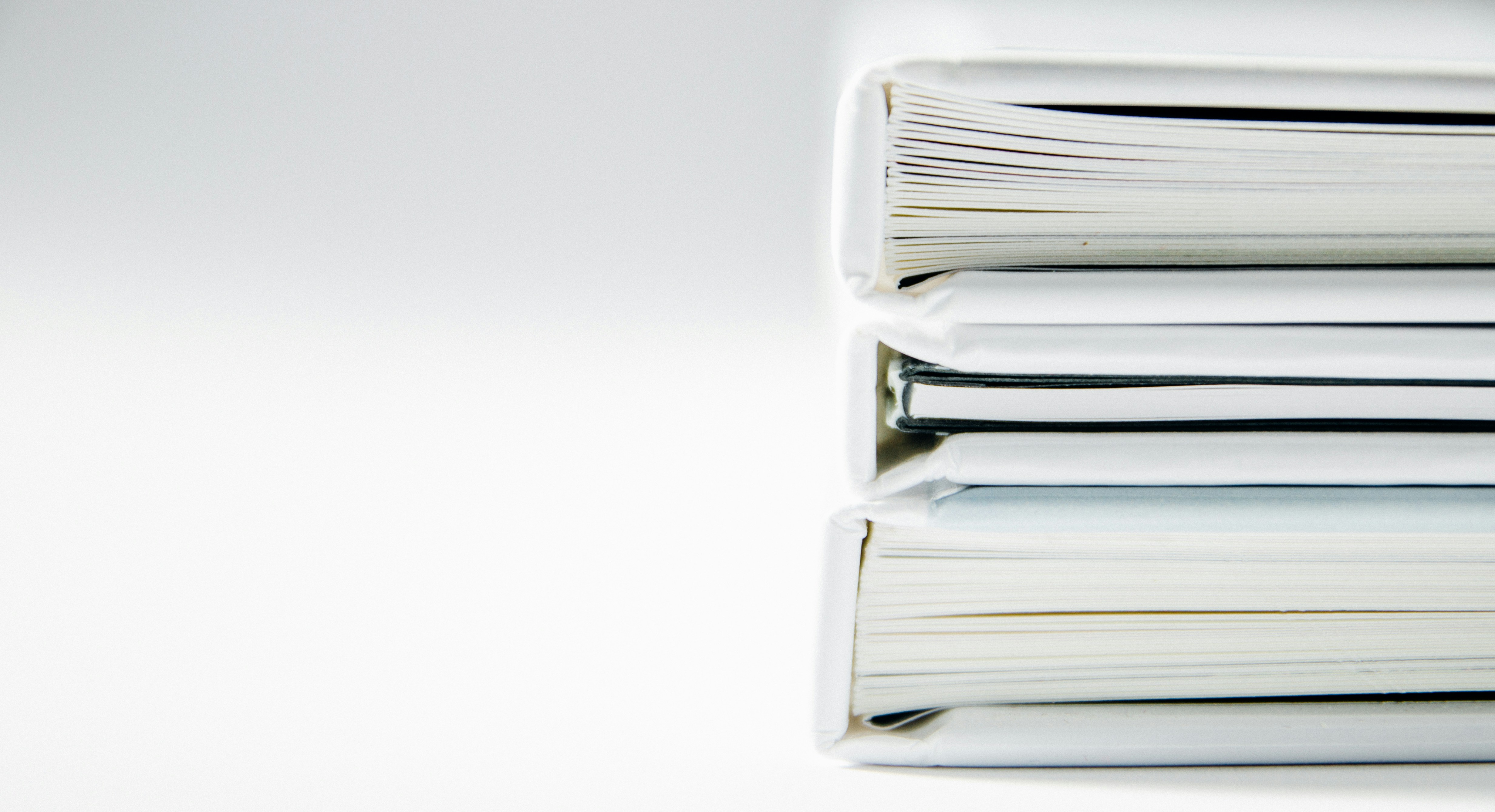 A stack of thick folders on a white surface.