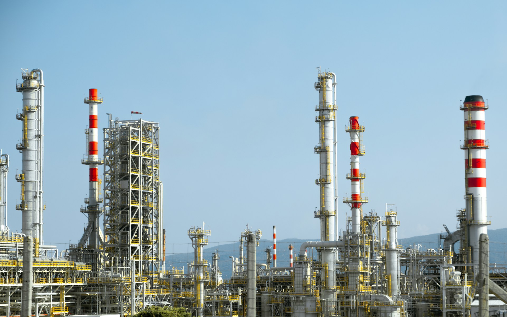The photo presents an industrial refinery during the day.