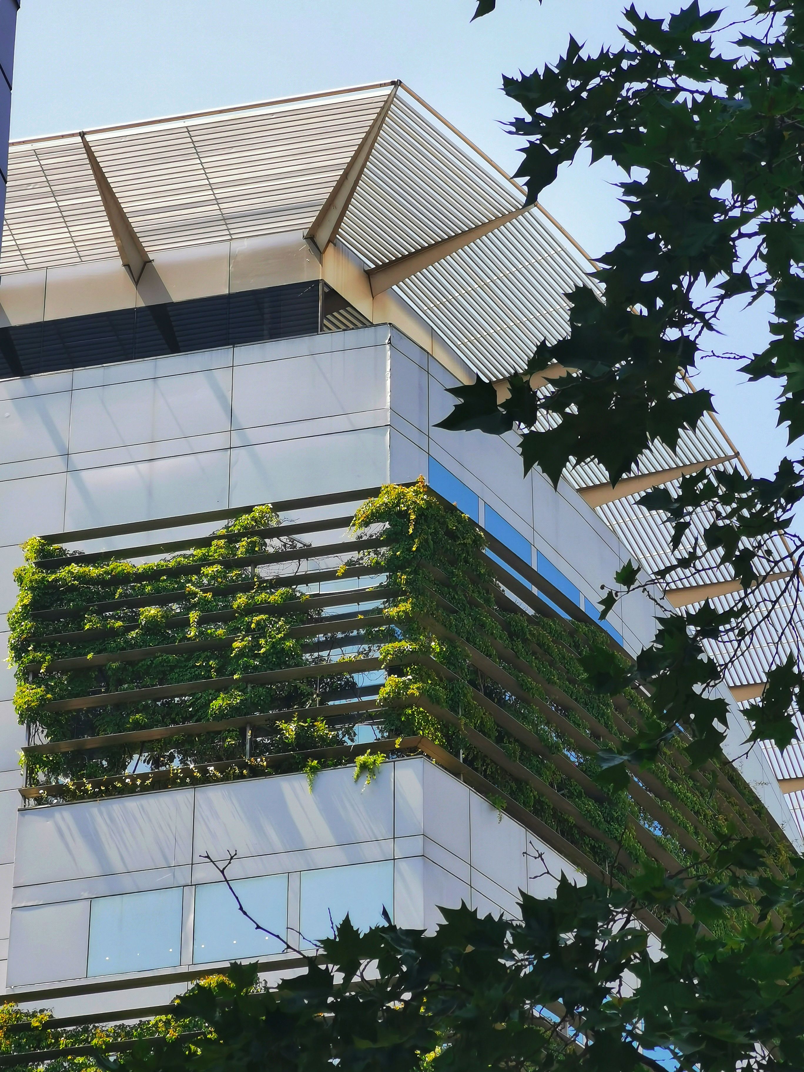 The picture shows a modern multi-storey building that incorporates extensive greenery into its façade and exterior design.
