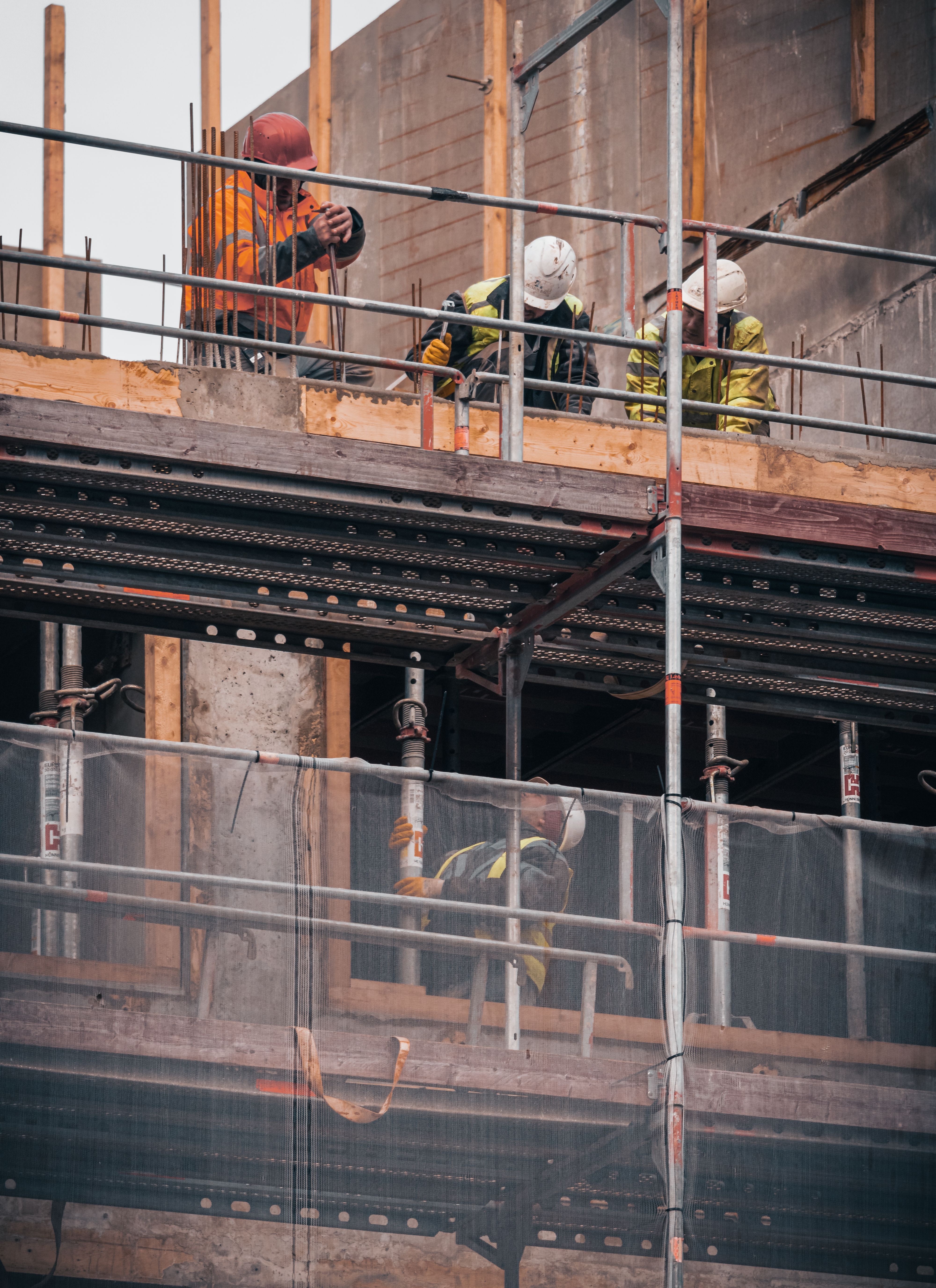 The picture shows construction workers carrying out building work on an elevated level of an active construction site.