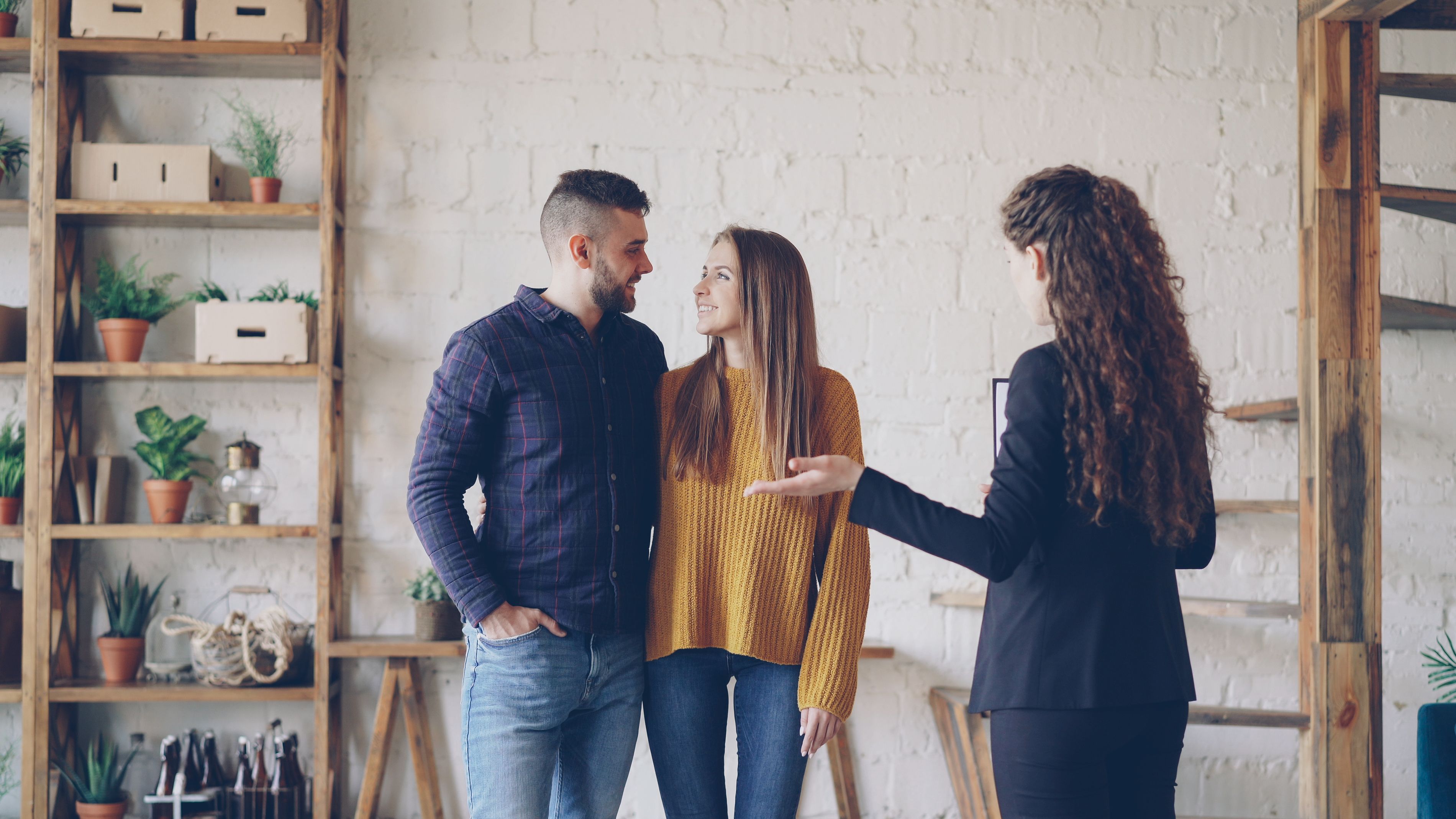 The picture shows an indoor property viewing or consultation, with three people standing in a bright, modern interior.
