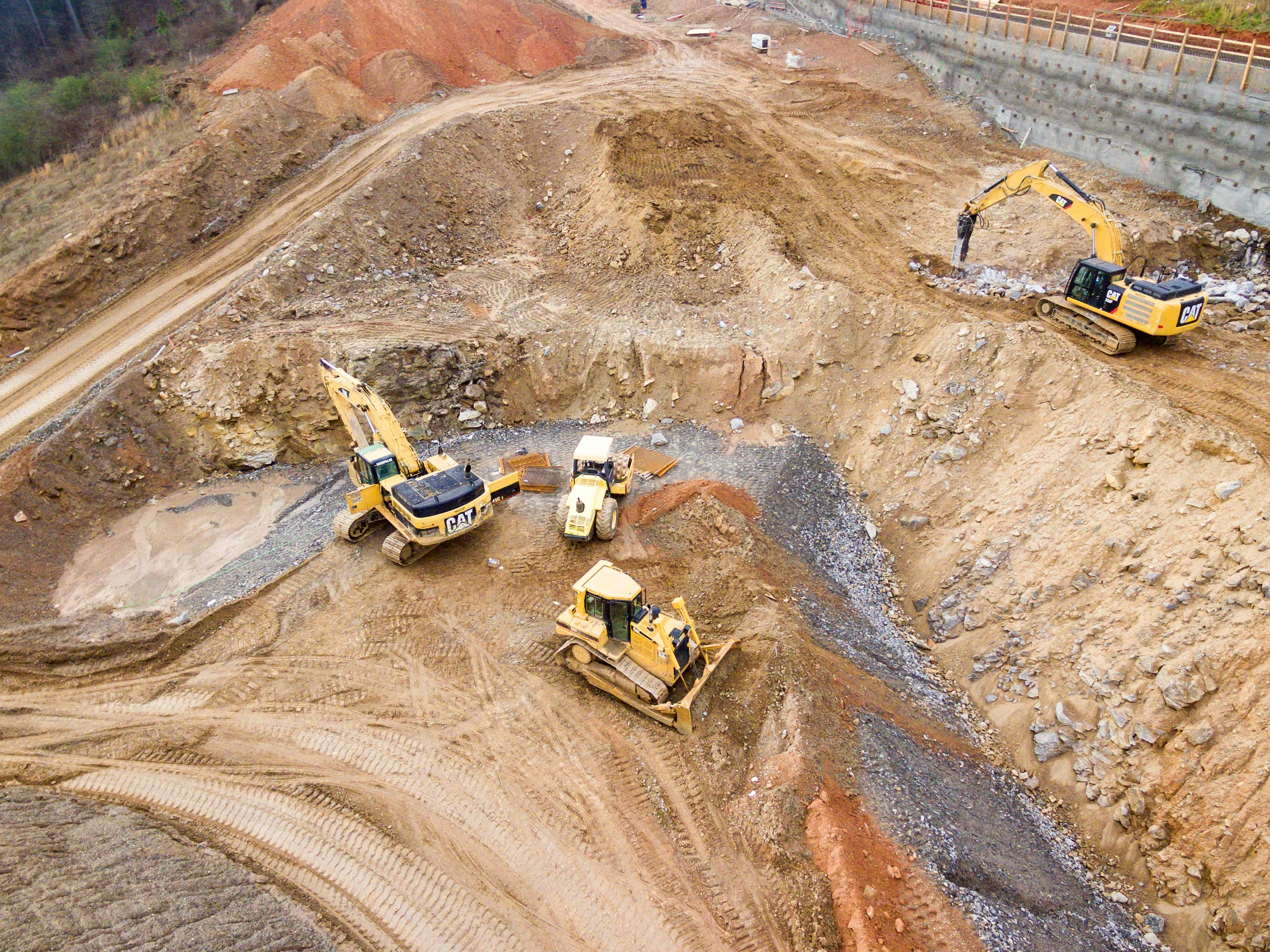 This picture shows heavy construction machinery, including excavators and a bulldozer, carrying out excavation and earthmoving work at a construction site.This picture shows heavy construction machinery, including excavators and a bulldozer, carrying out excavation and earthmoving work at a construction site.