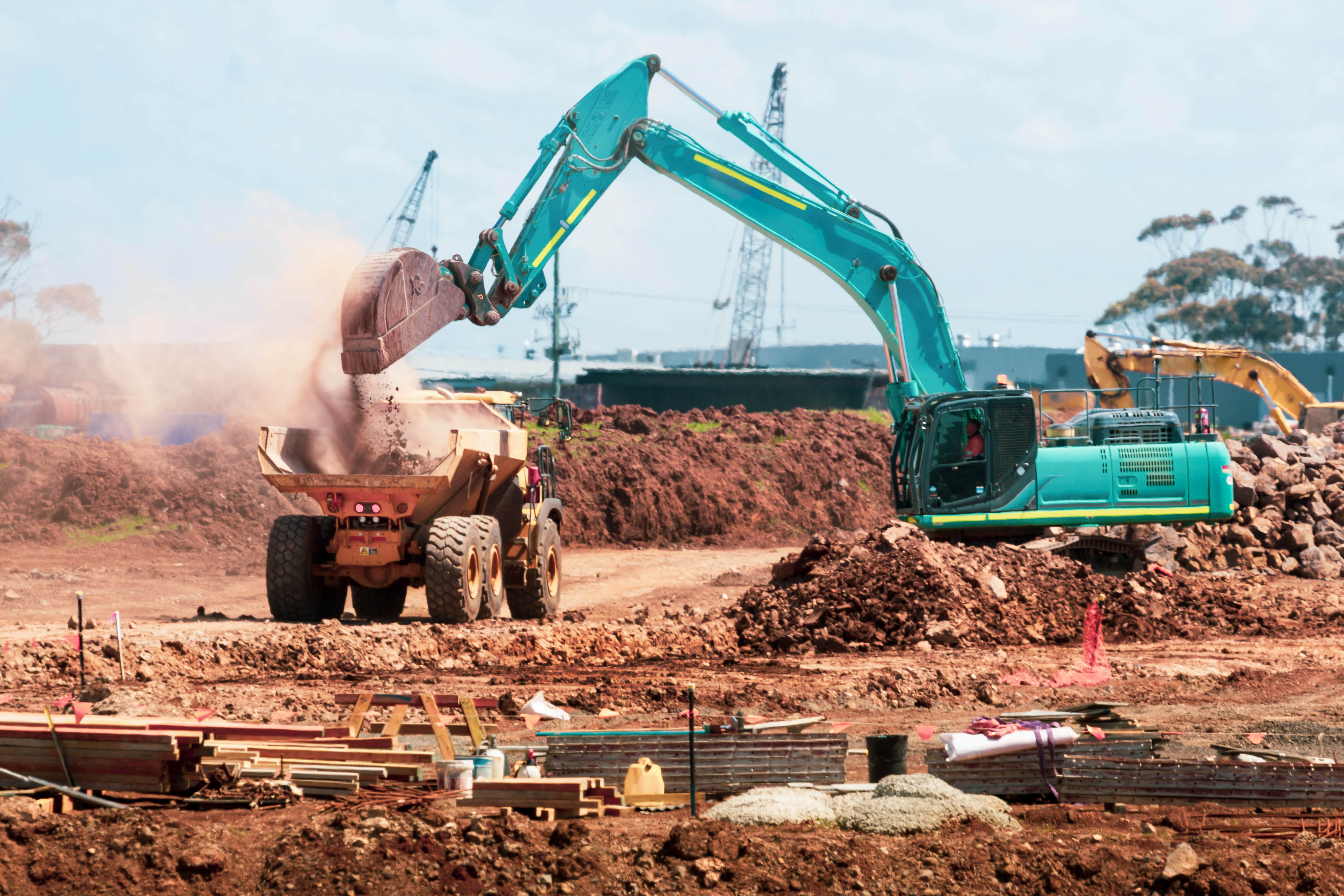 This picture shows an excavator loading soil into a dump truck at an active construction site.