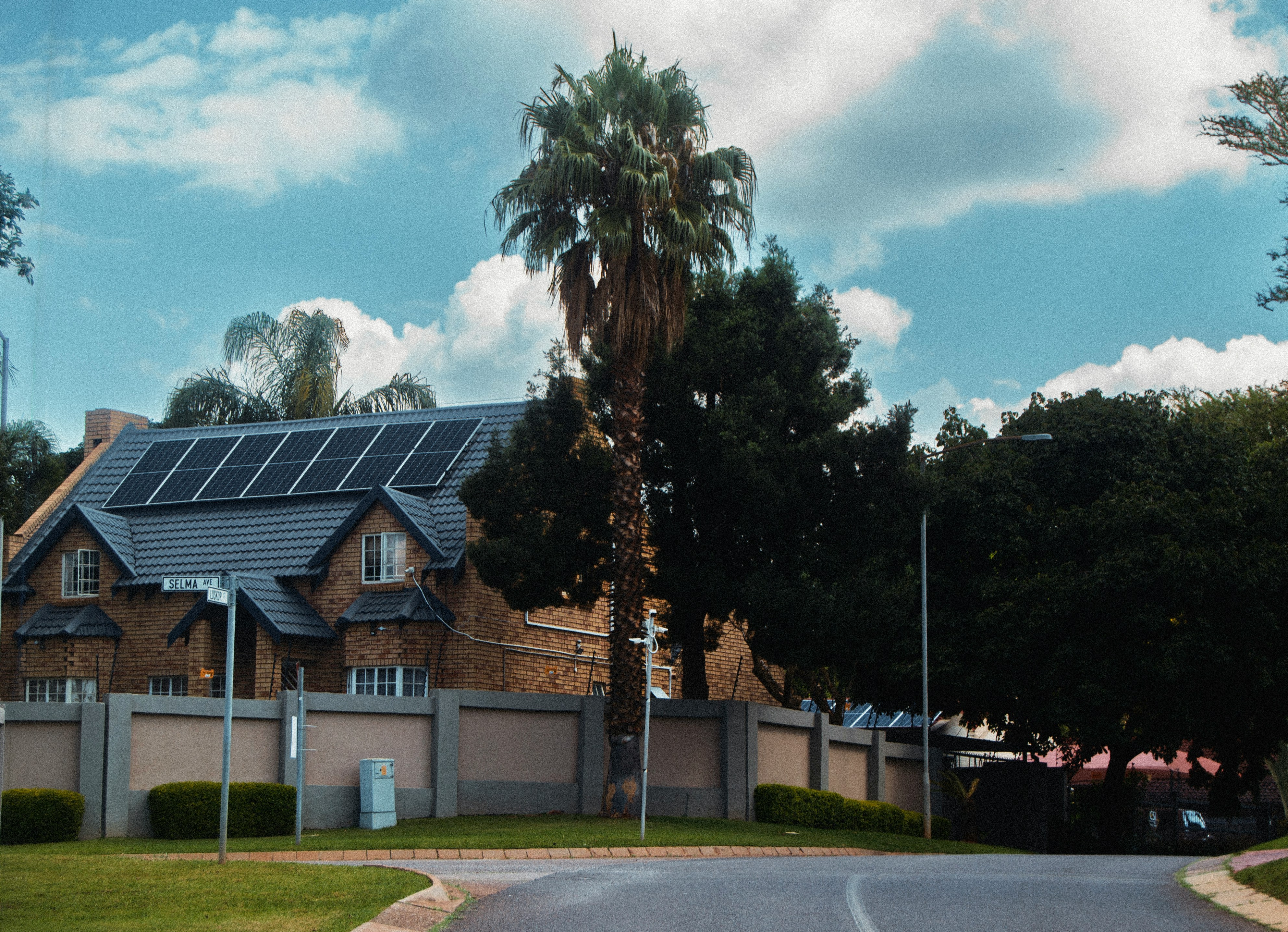 This picture shows a residential house with solar panels installed on the roof, surrounded by trees and greenery.