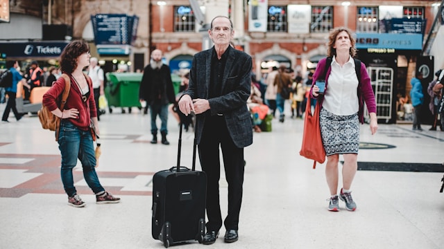 An illustrative photo of a man standing and holding his luggage bag