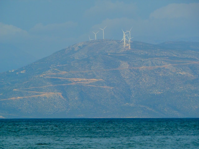 An illustrative photo of a white sailboat gliding on the sea near a mountain