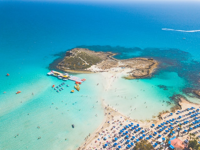 An illustrative photo of a beach scene with numerous blue umbrellas in Cyprus.