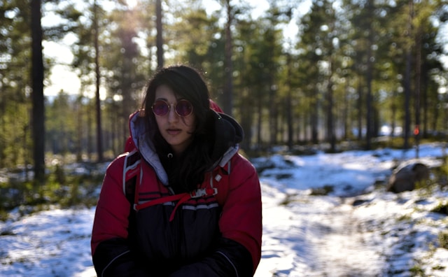 An illustrative photo of a woman in a jacket standing in a snowy landscape