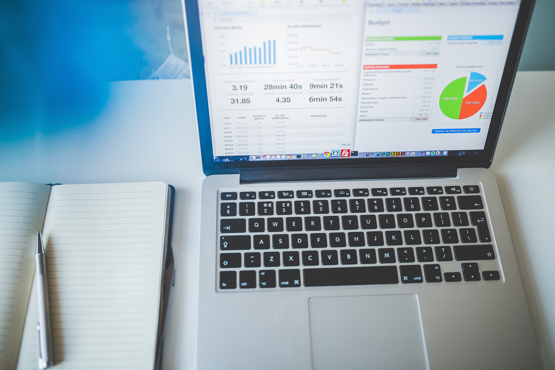 An illustrative photo of a laptop and notebook with business charts.