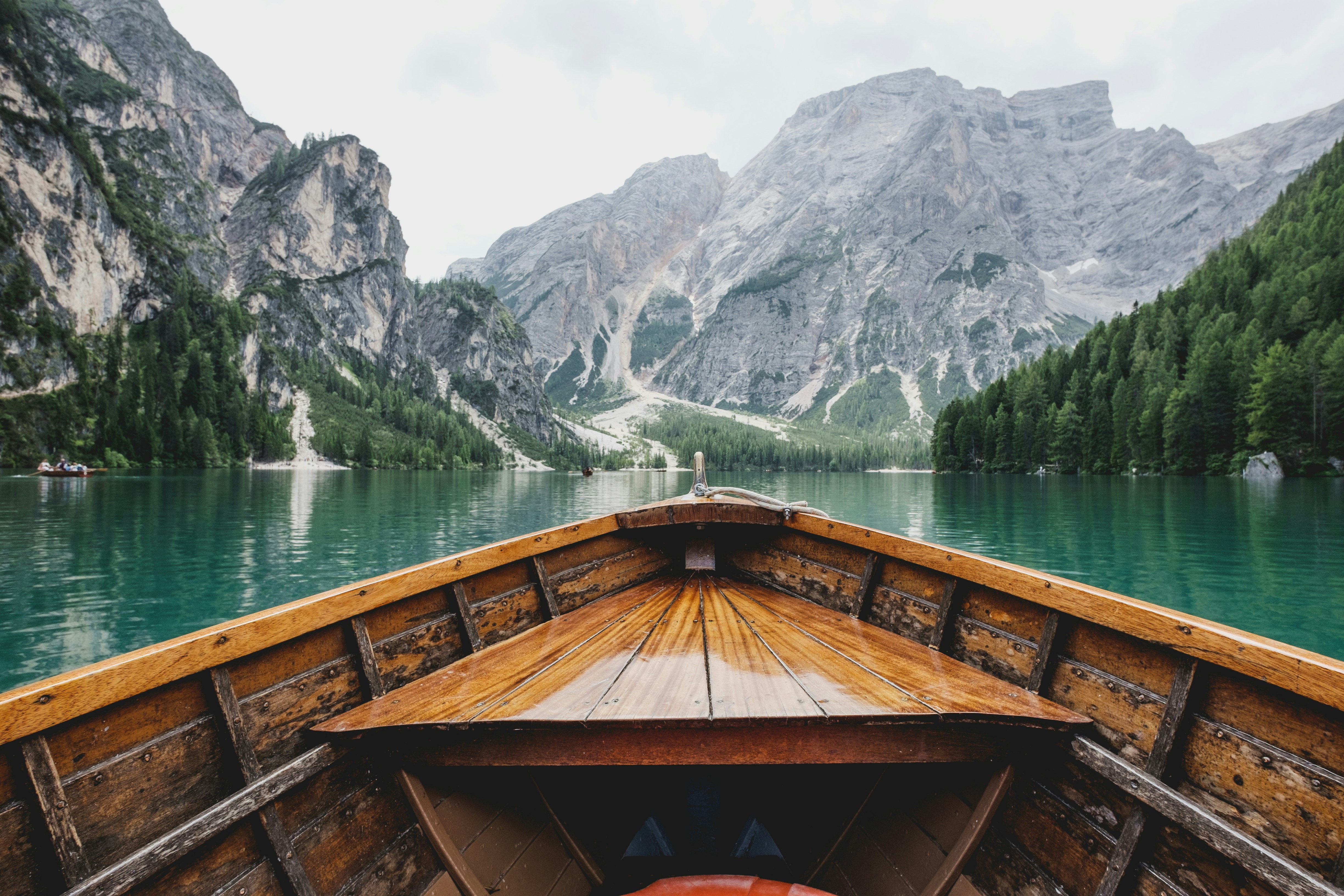 An illustrative photo of a brown wooden boat moving towards a mountain