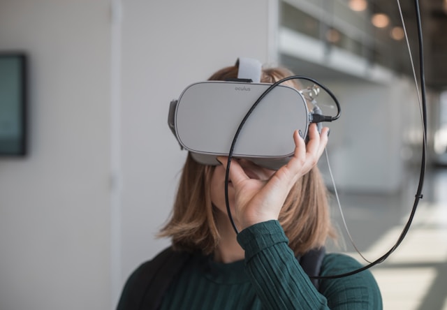 An illustrative photo of a woman in black sweater holding white vr goggles