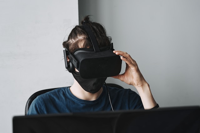 An illustrative photo of a man wearing black VR goggles, immersed in a virtual reality experience