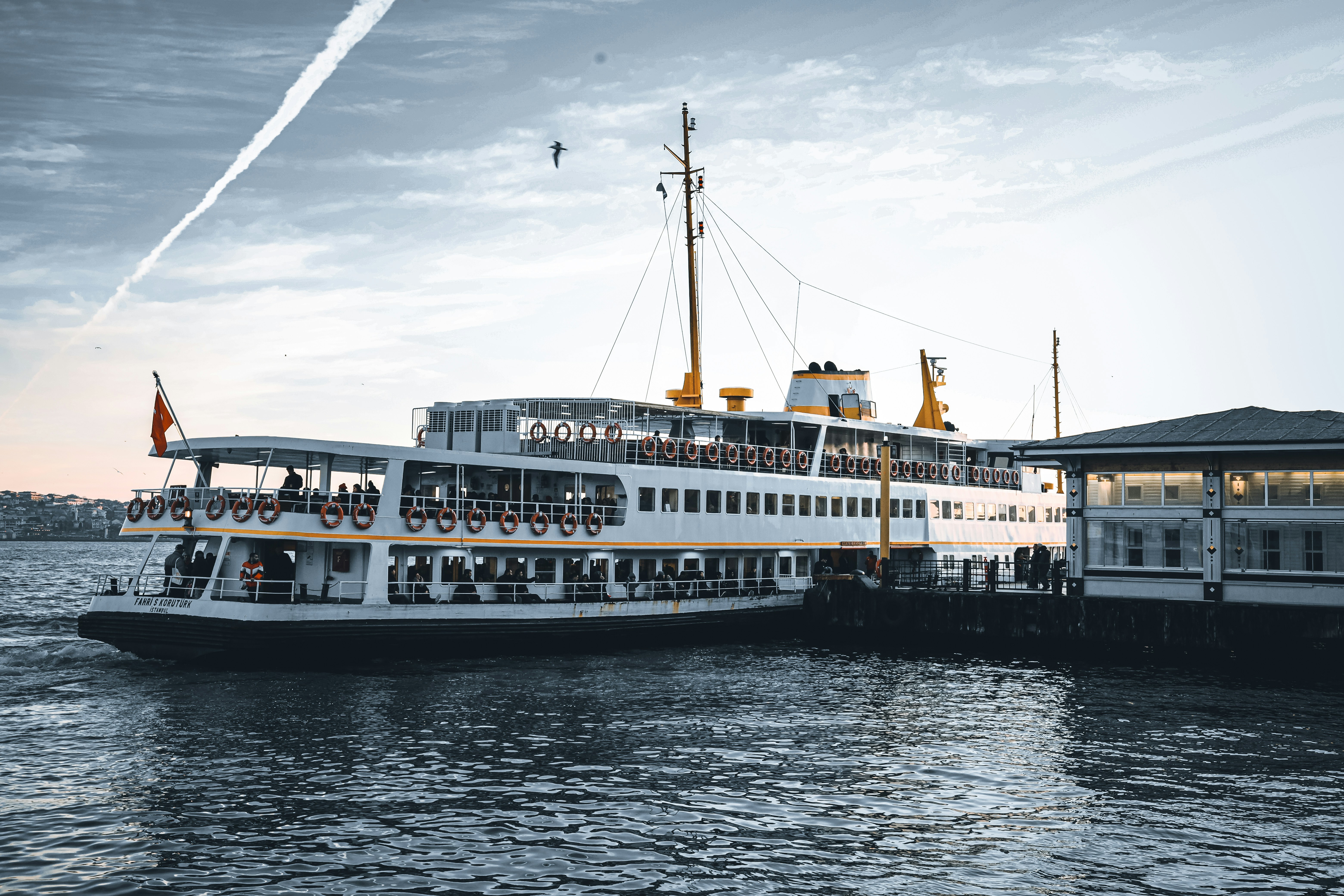 An illustrative photo of a white and black ship on the sea under white clouds during daytime