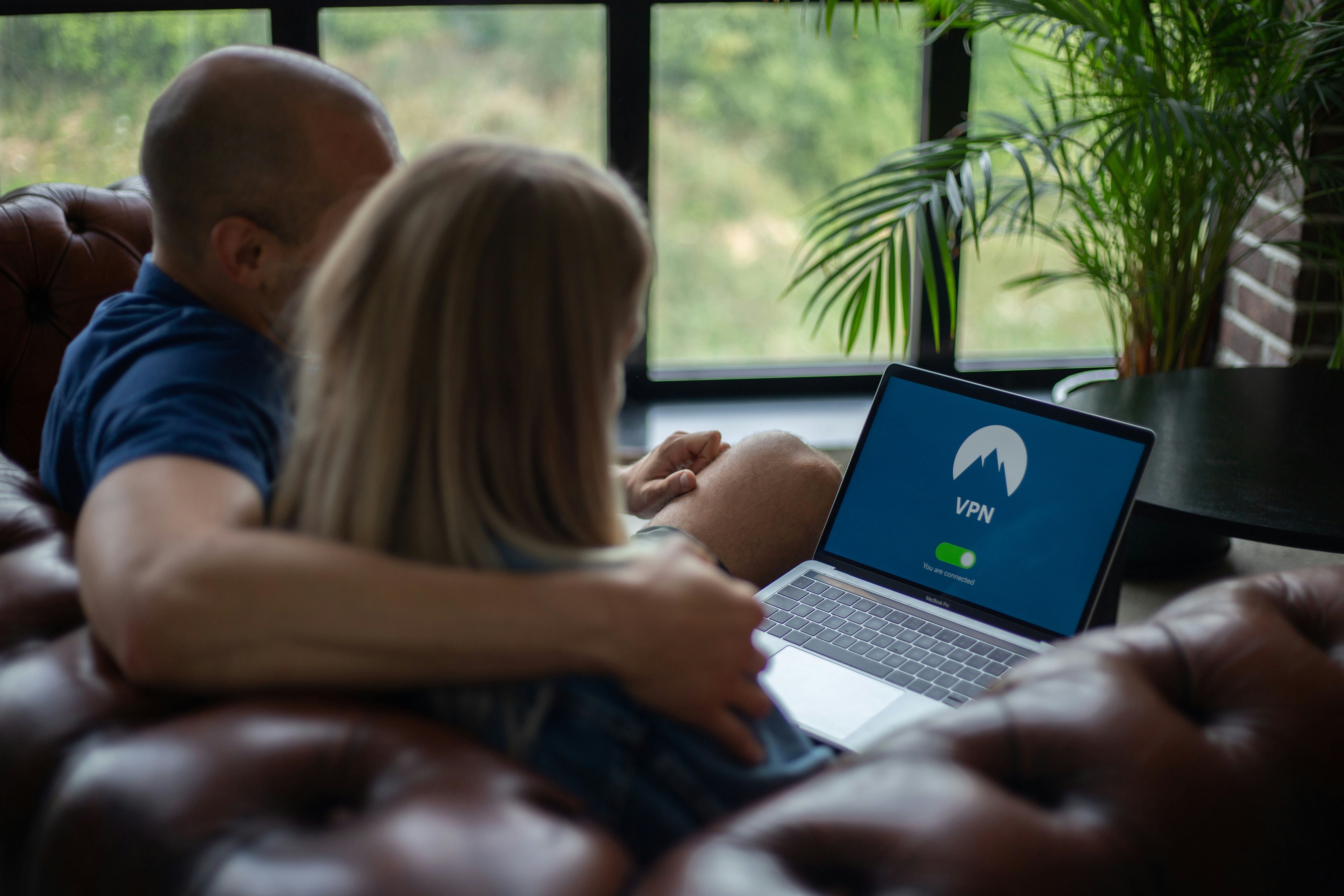 An illustrative photo of a man and woman sitting on chair in front of macbook pro