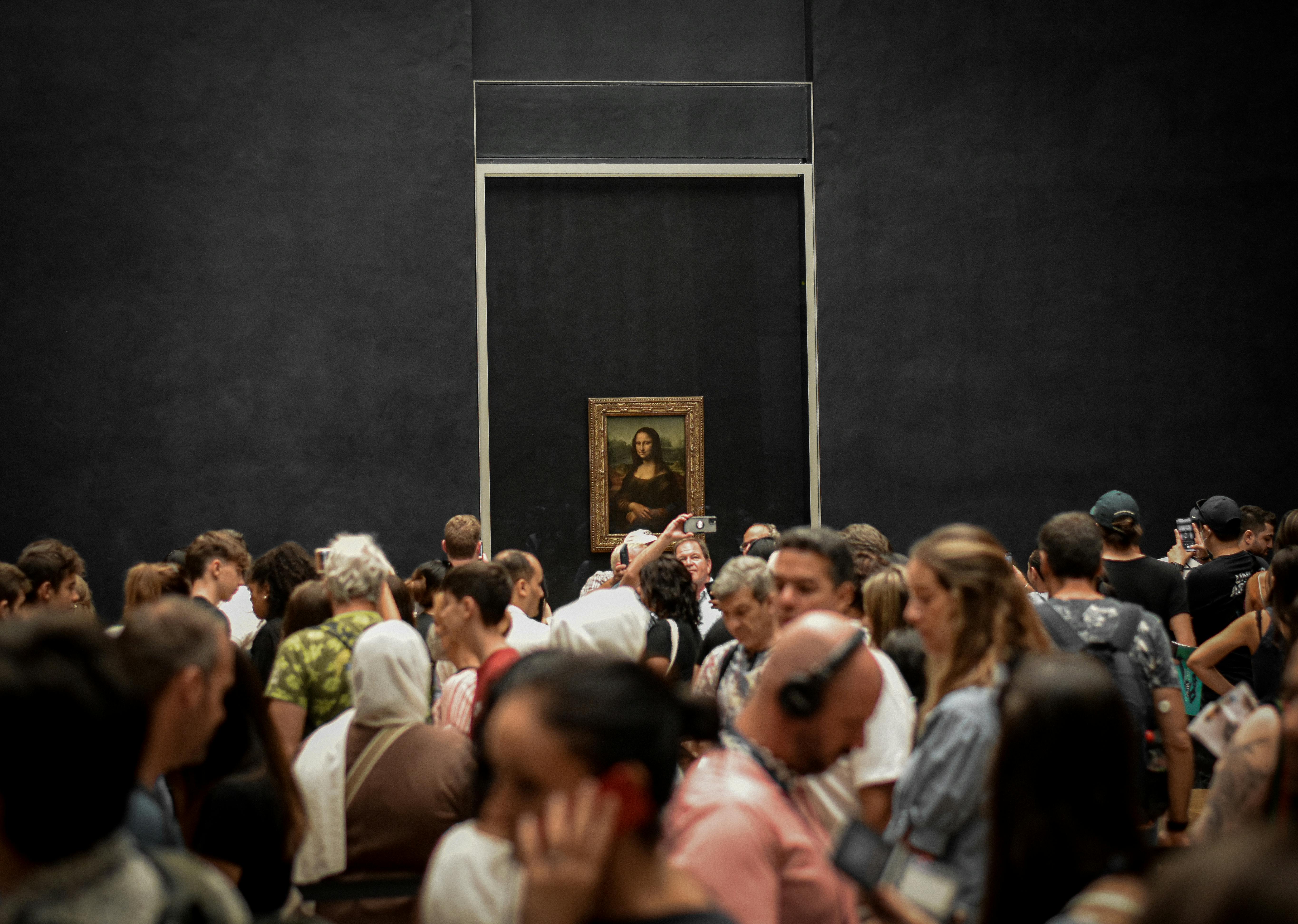 An illustrative photo of a crowd of visitors viewing the Mona Lisa painting at the Louvre