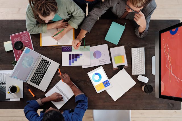 An illustrative photo of a top-down view of four individuals around a table during a collaborative work session. 