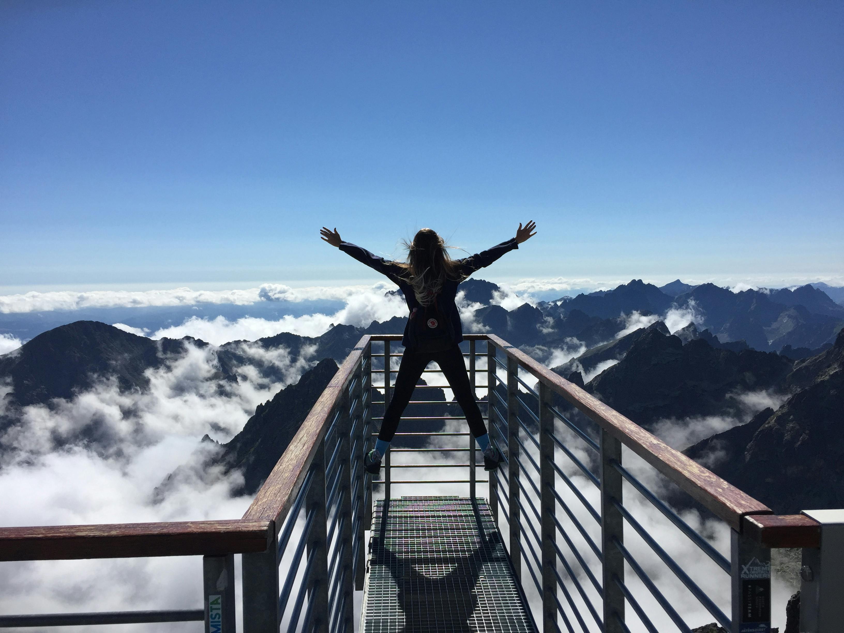 Photo by Pexels An illustrative photo of a person standing on a viewing platform with mountains visible