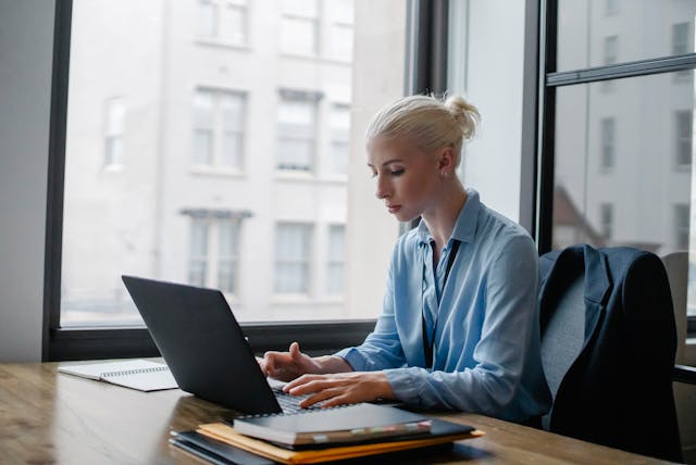 An illustrative photo of a woman is typing on her laptop