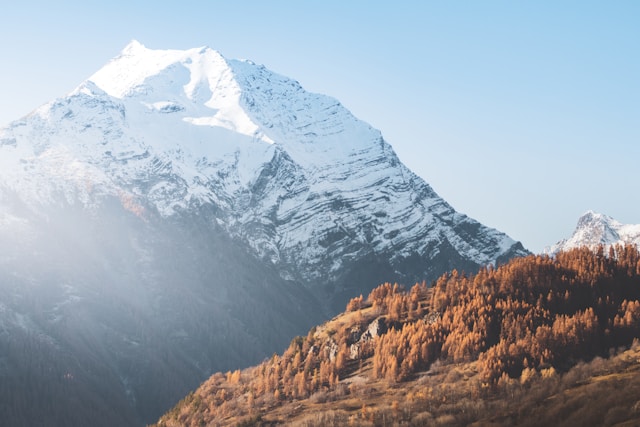 An illustrative photo of brown and white mountains under a clear blue sky