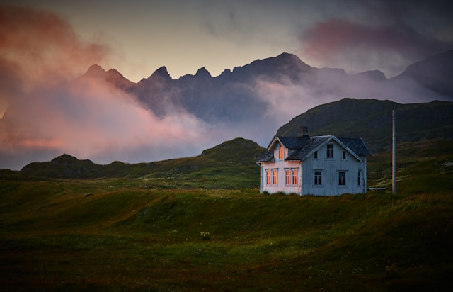 An illustrative photo of a white and gray house near mountain.