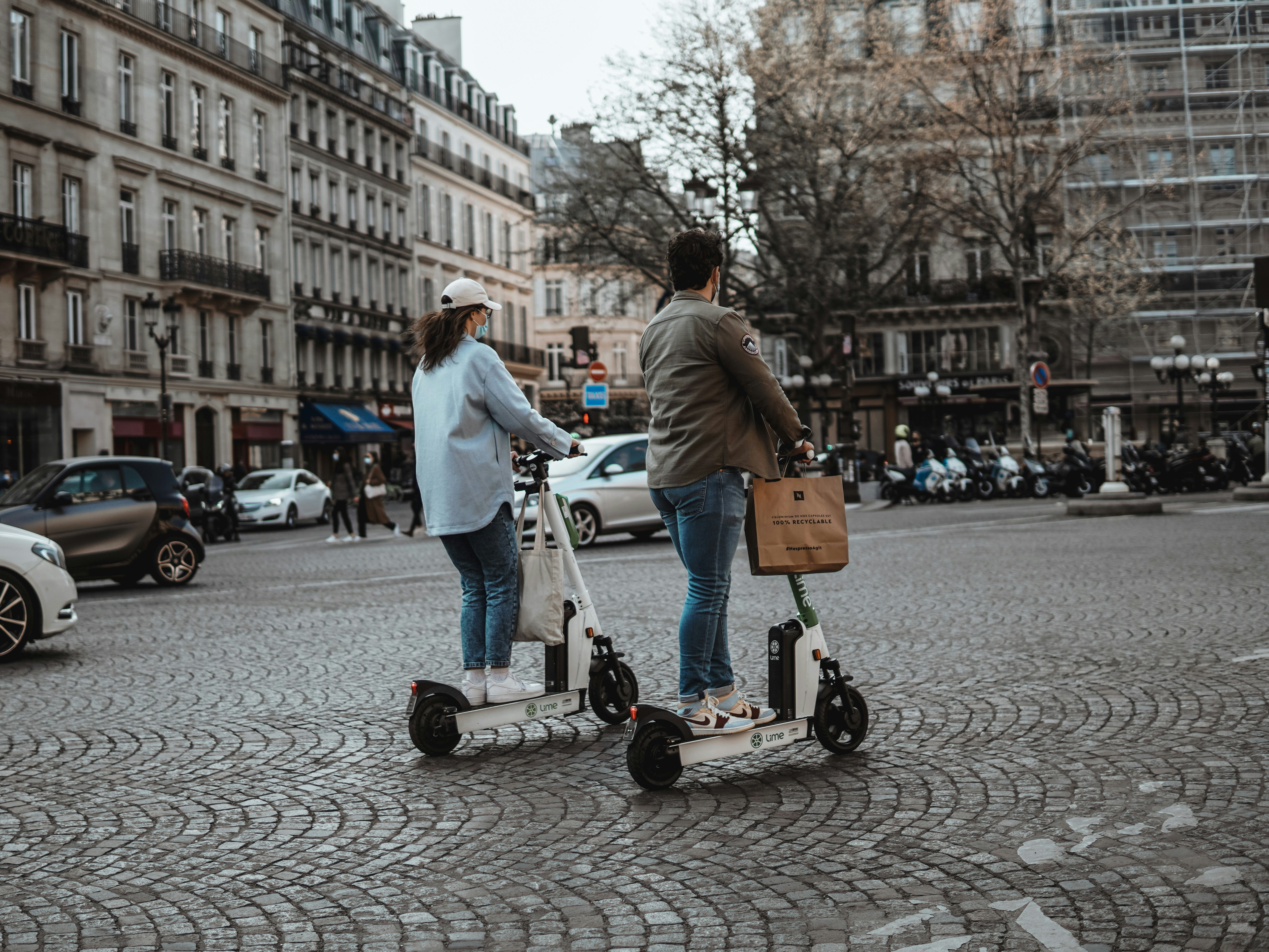 An illustrative photo of two individuals riding electric scooters on a paved street