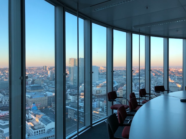 An illustrative photo of people sitting on chairs near a large glass window during the daytime