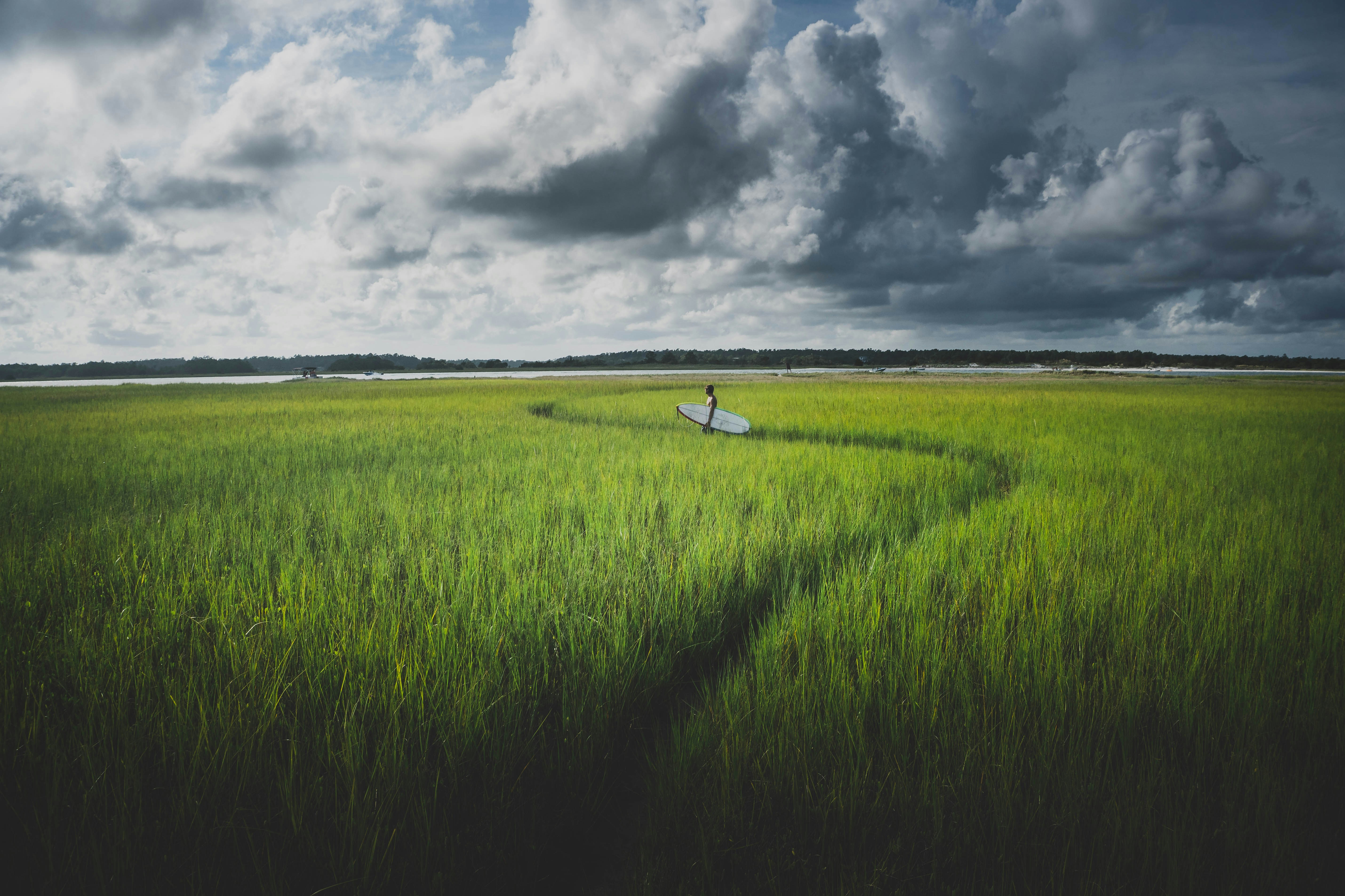 An illustrative photo of a person with a surfboard in the green field