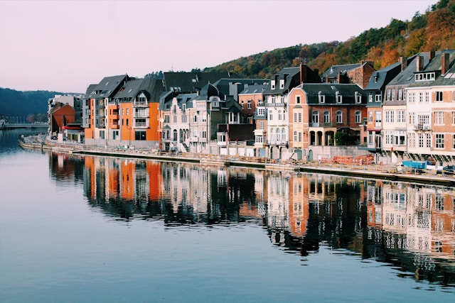 An illustrative photo of assorted colorful houses line the shore of a serene lake.