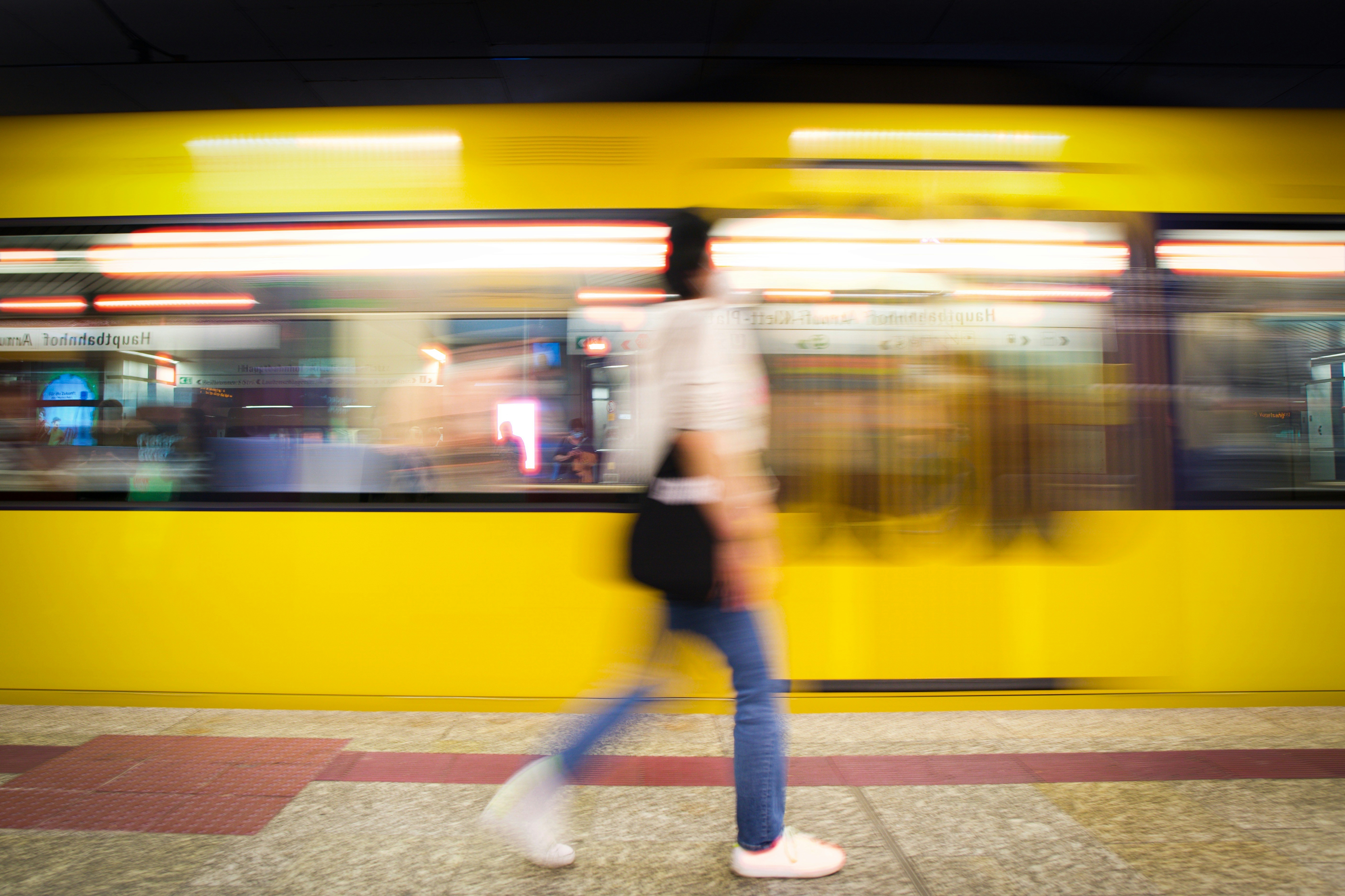 An illustrative photo of a person walking in front of a yellow train