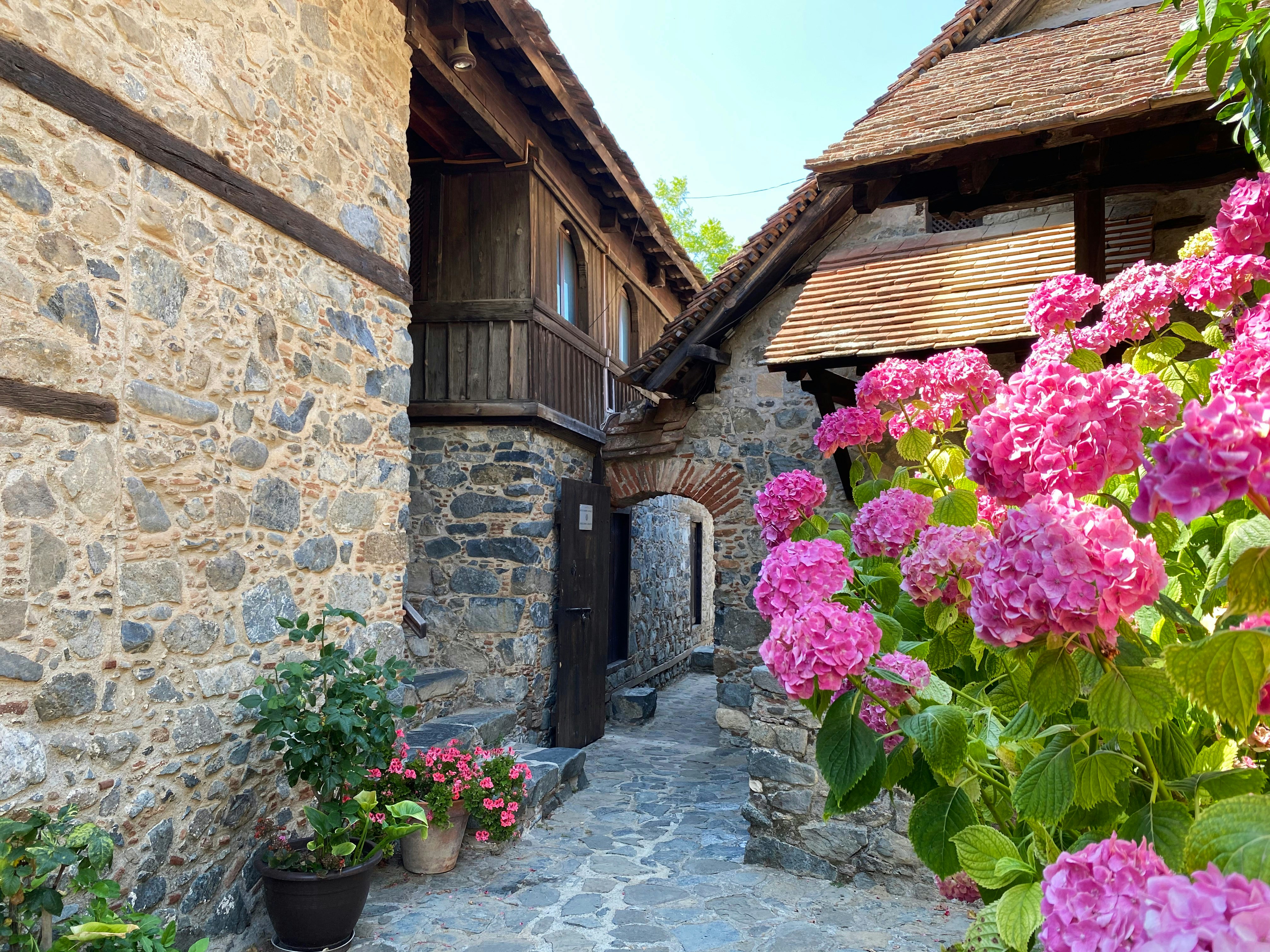 An illustrative photo of pink flowers in front of brown brick house.
