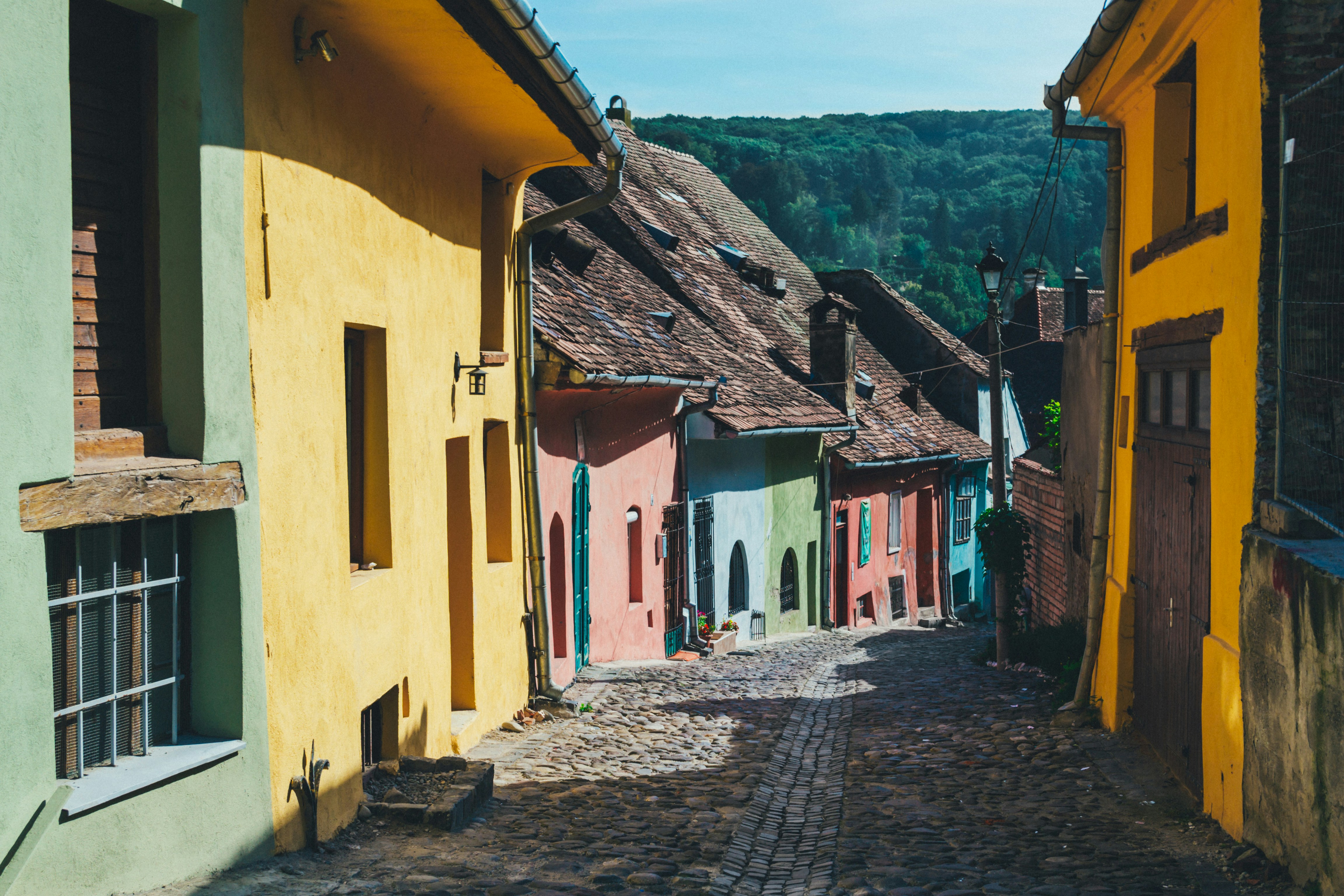 An illustrative photo of a narrow street between yellow and green houses