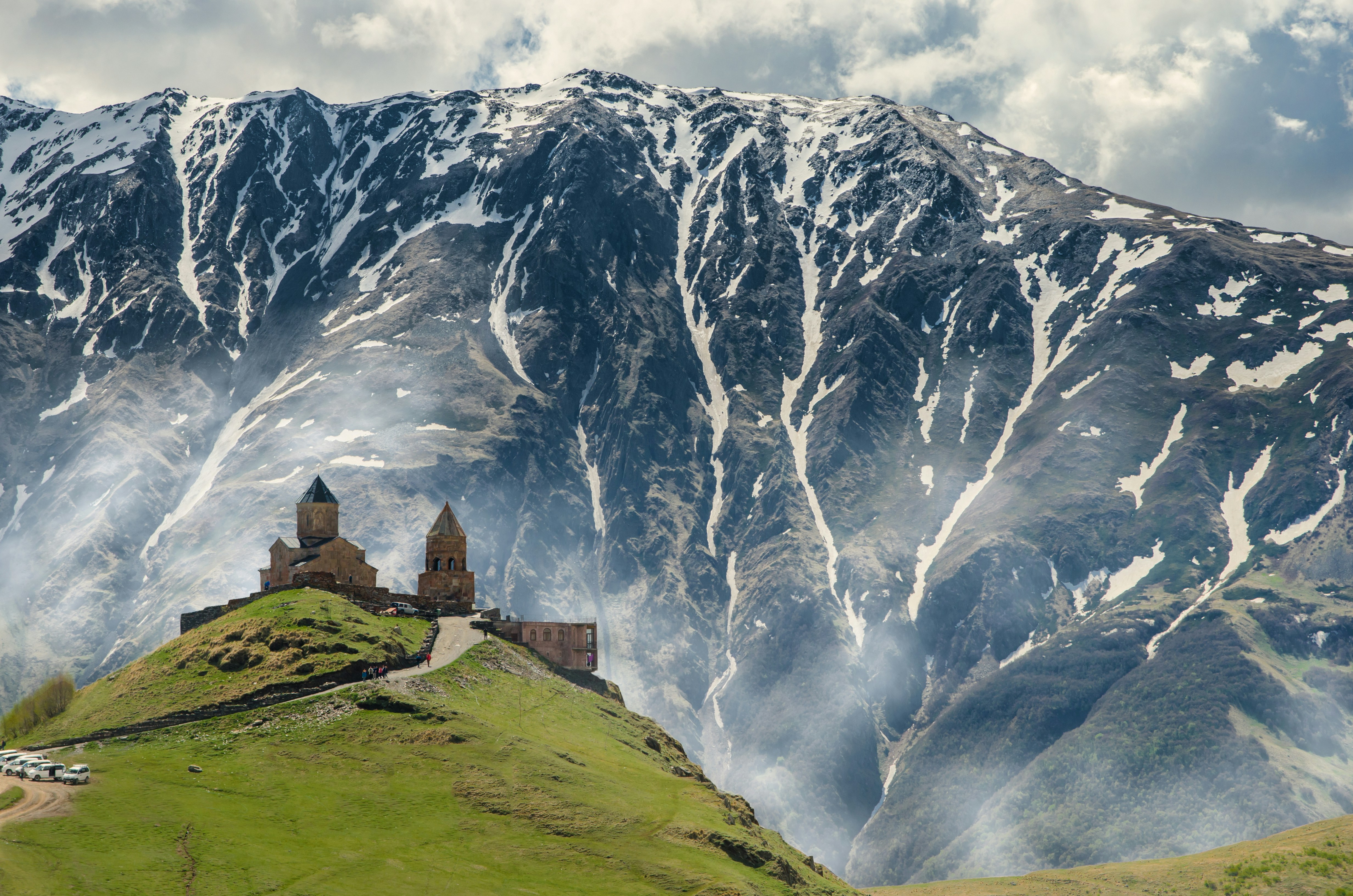 An illustrative photo of a church on a hill with a big snowy mountain in the background.