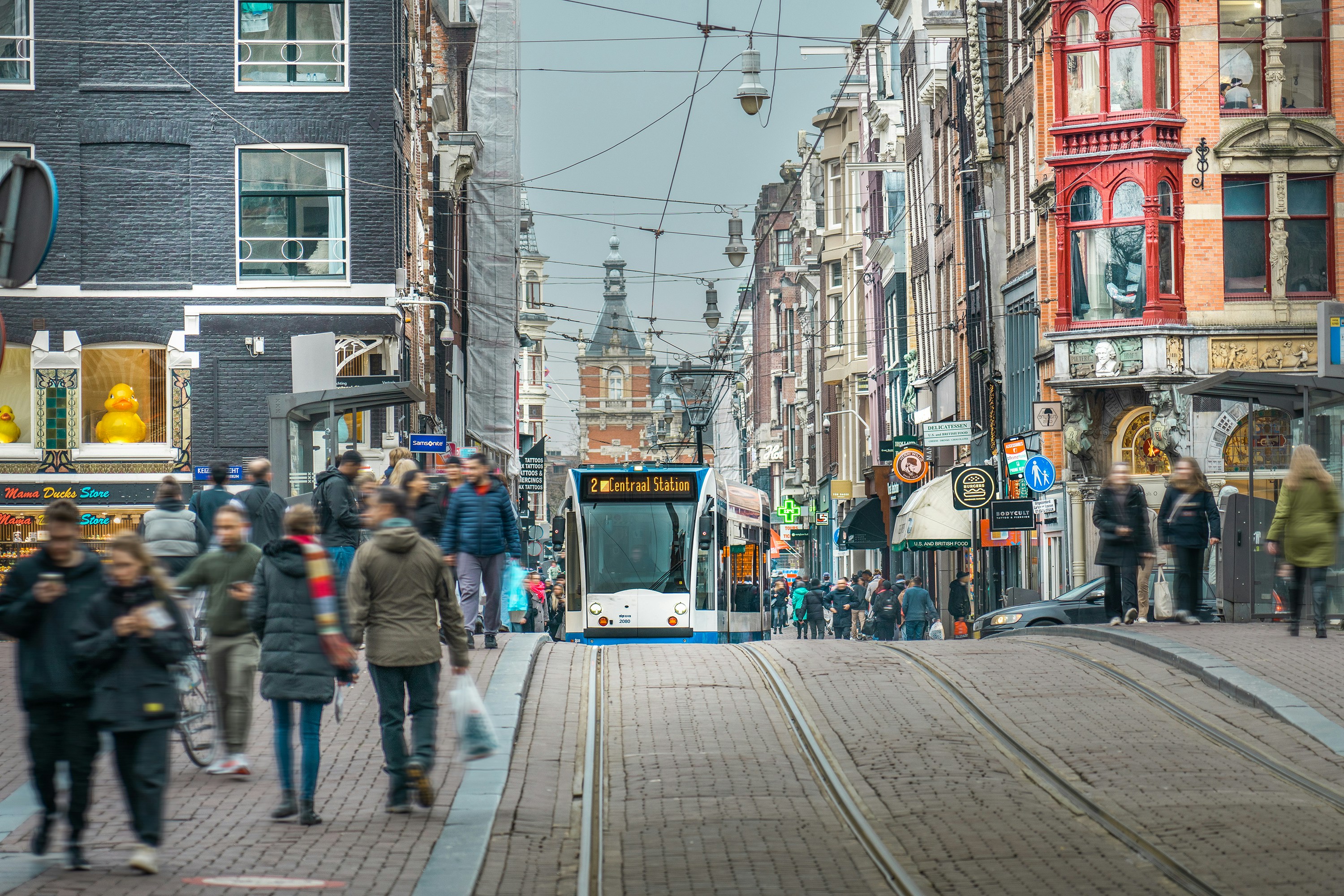 Photo by Unsplash An illustrative photo of a group of people walking down a street next to tall buildings