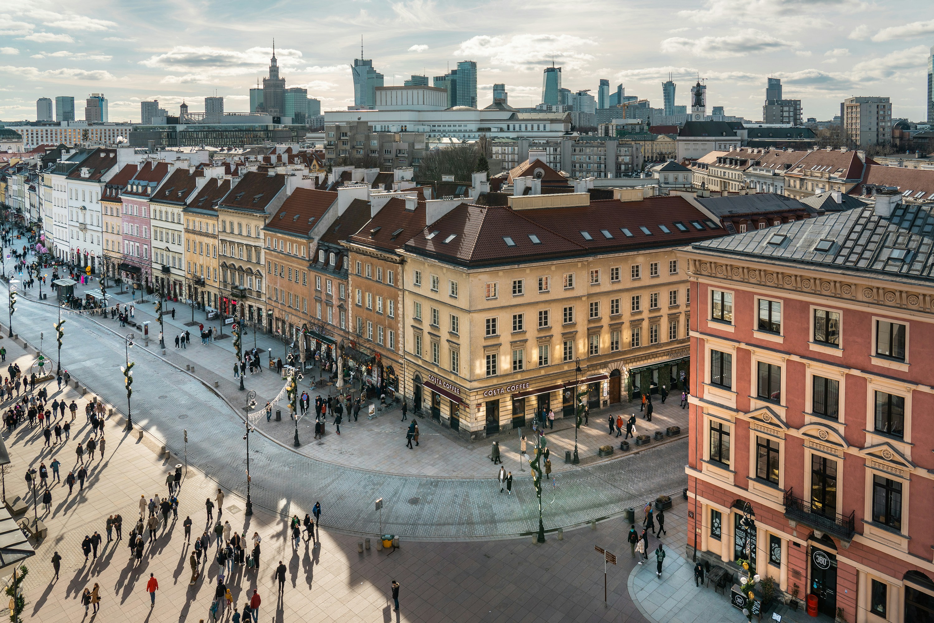 Photo by Unsplash An illustrative photo of a group of people walking down a street next to tall buildings.