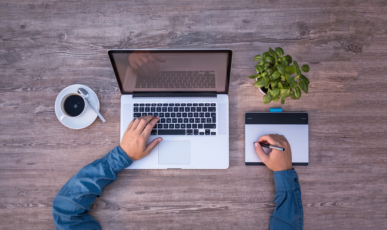 An illustrative photo of a person typing on a laptop while writing notes