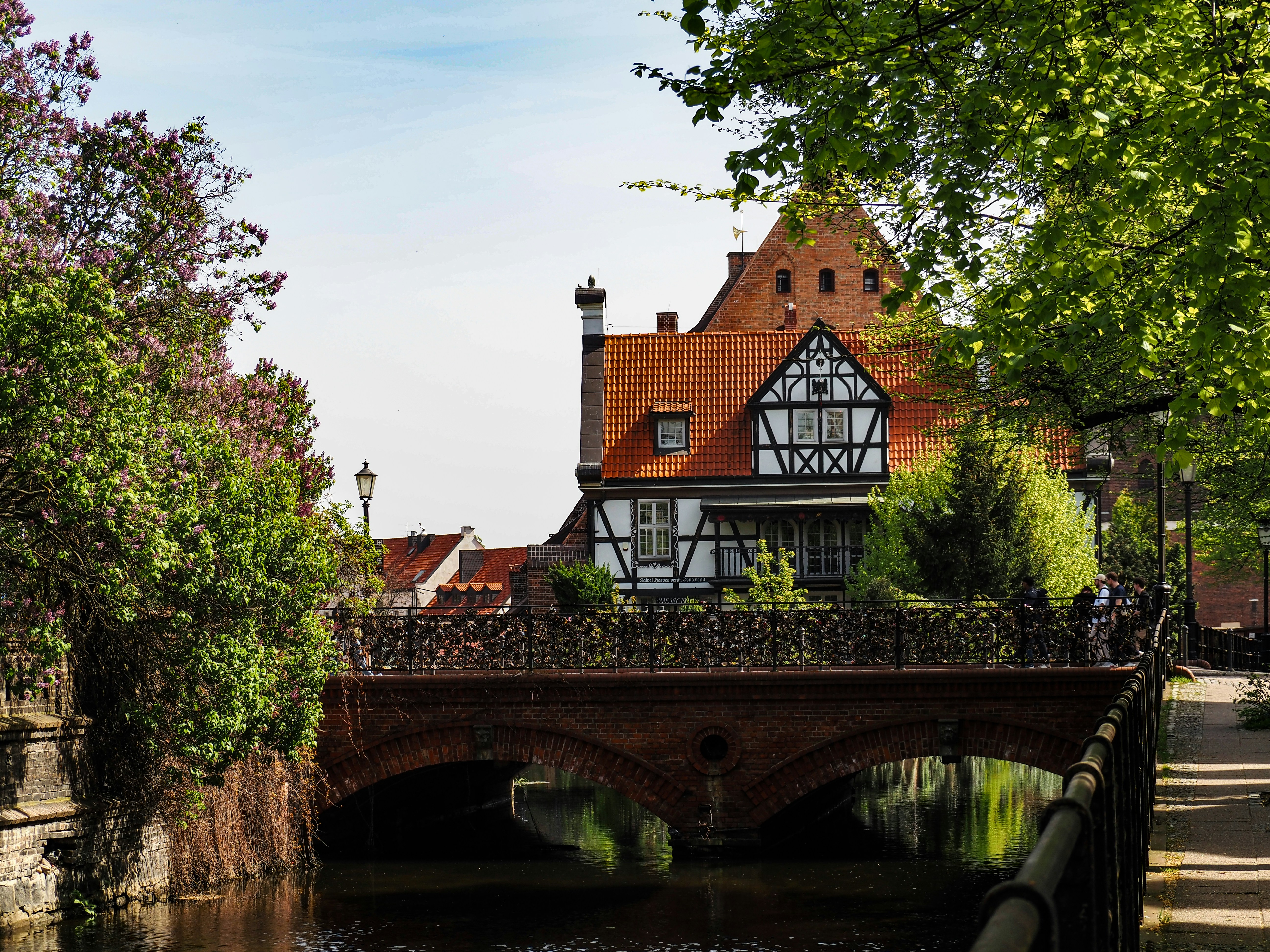 An illustrative photo of a bridge over a river with a house in the background.