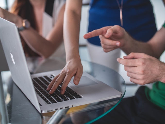 An illustrative photo of a person touching and pointing at a MacBook Pro