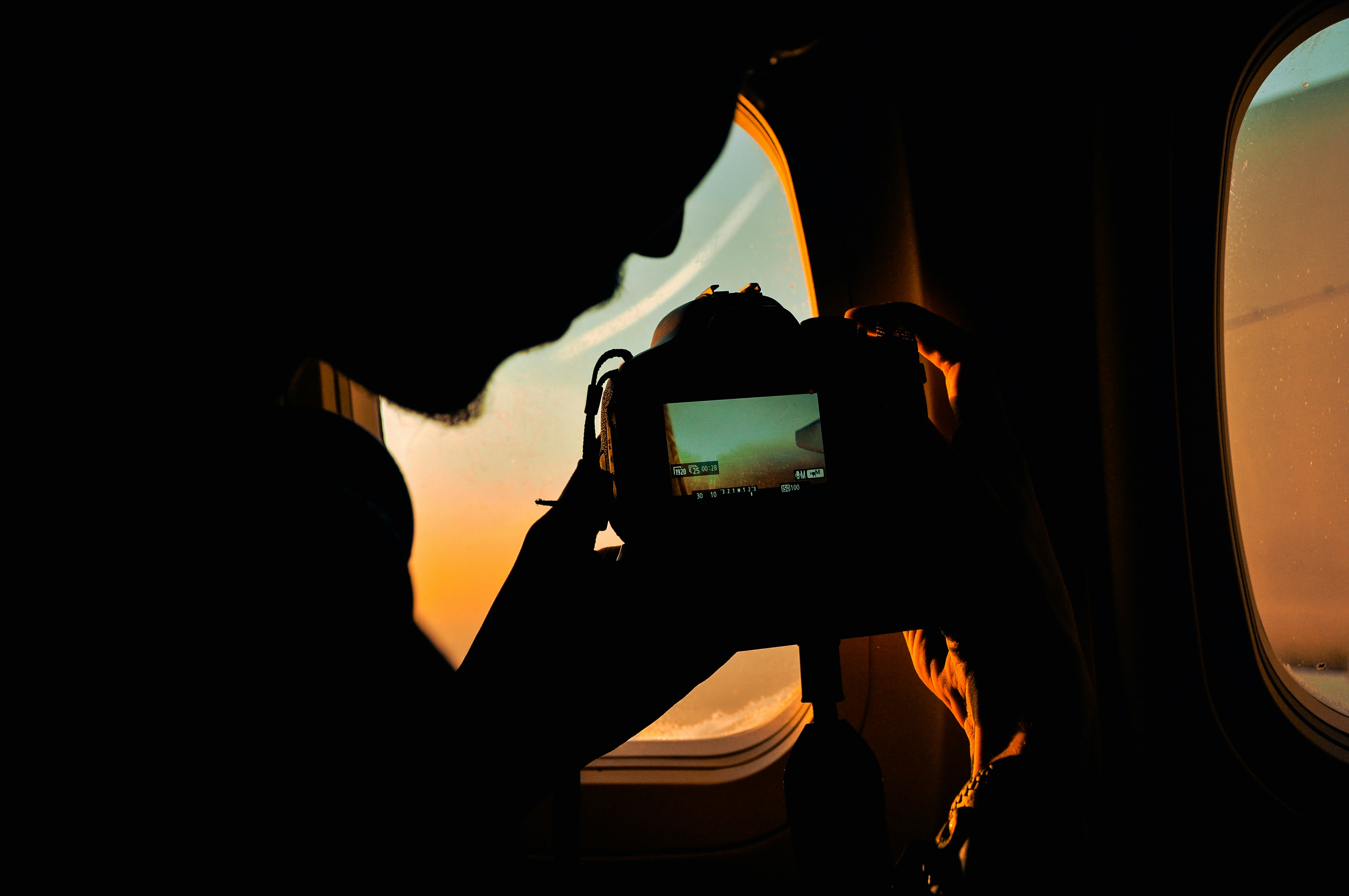 An illustrative photo of a person taking a picture of a plane window.