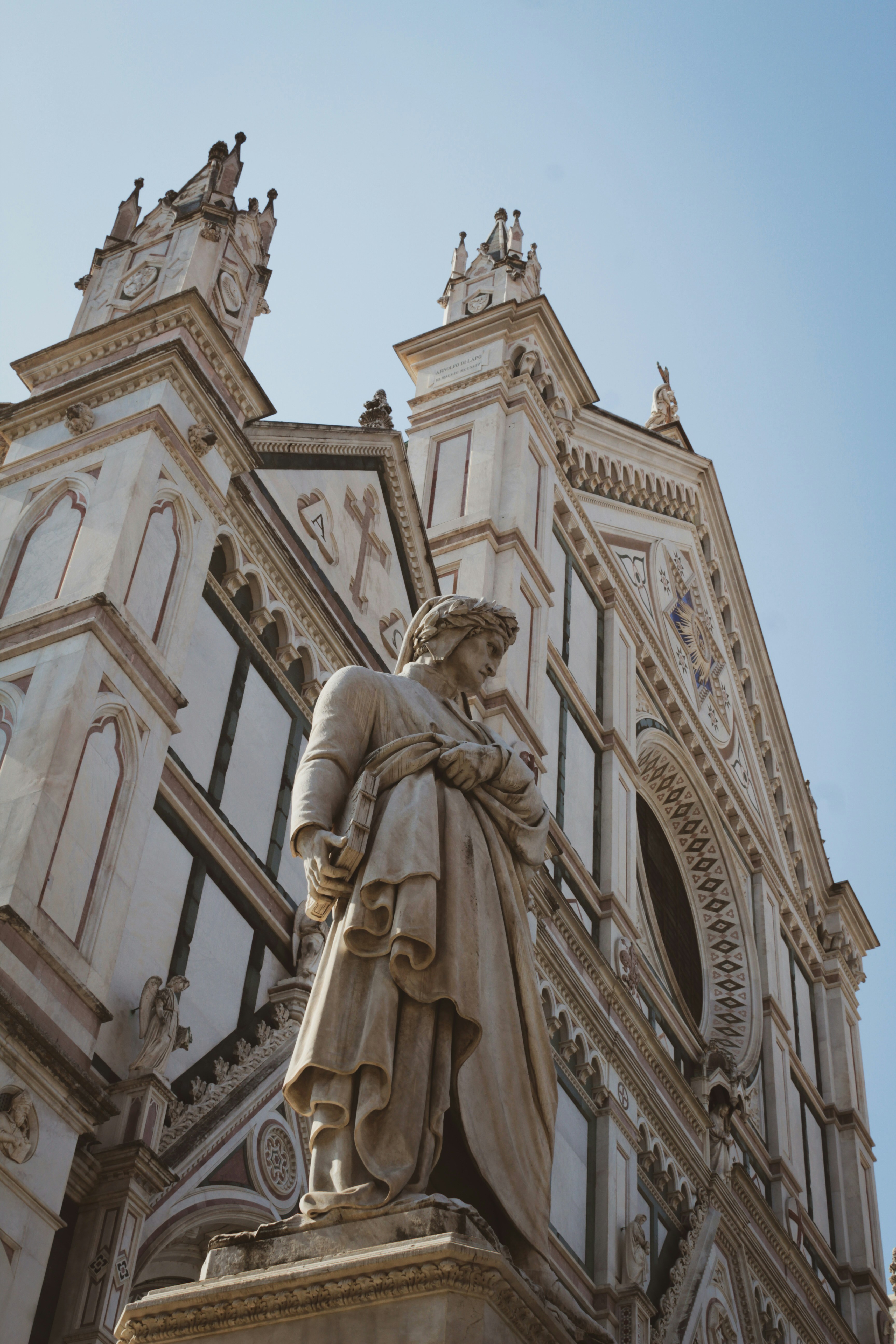 An illustrative photo of a statue of a man holding a book in front of a building