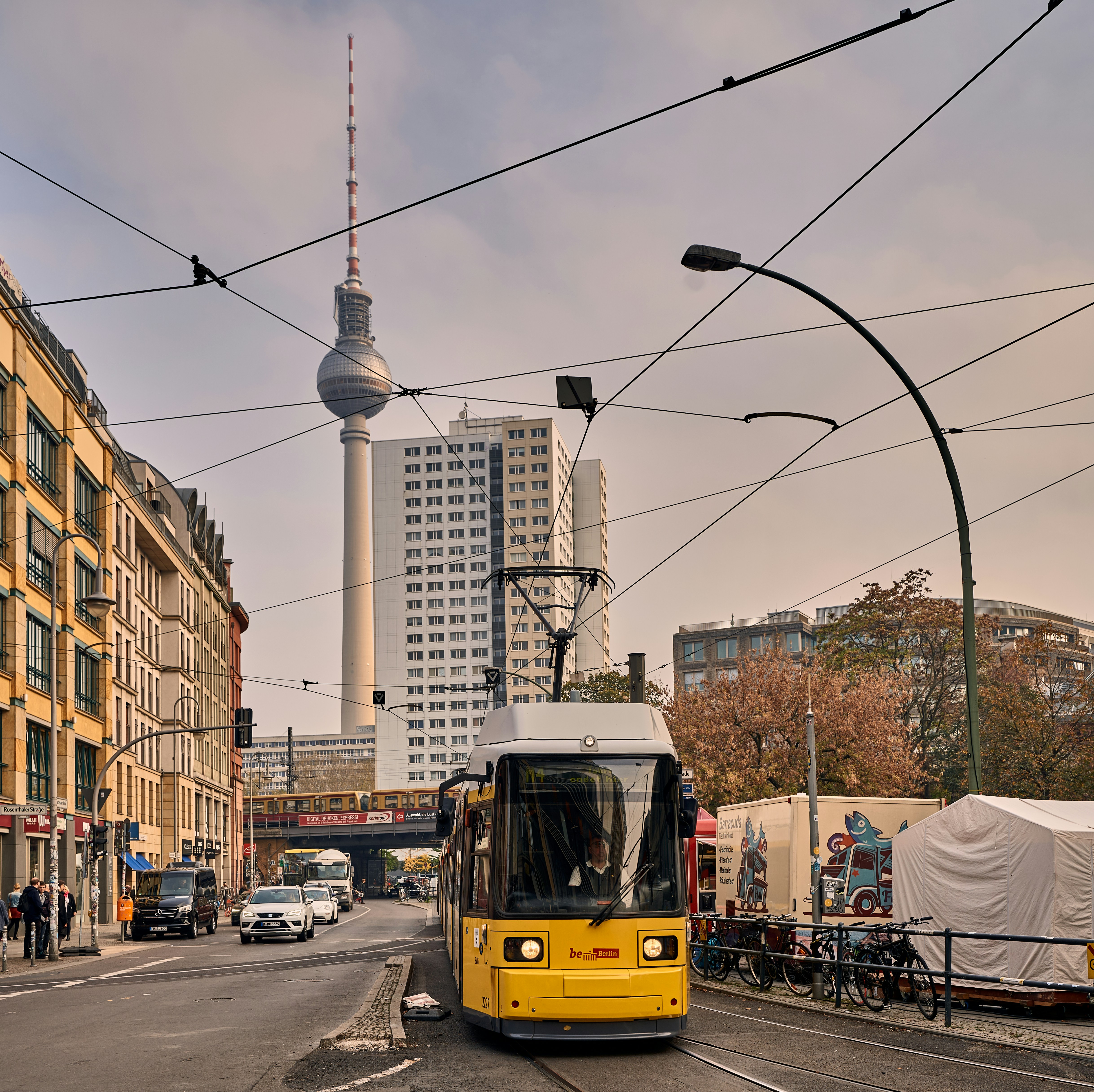 An illustrative photo of a yellow tram on a city street with overhead cables