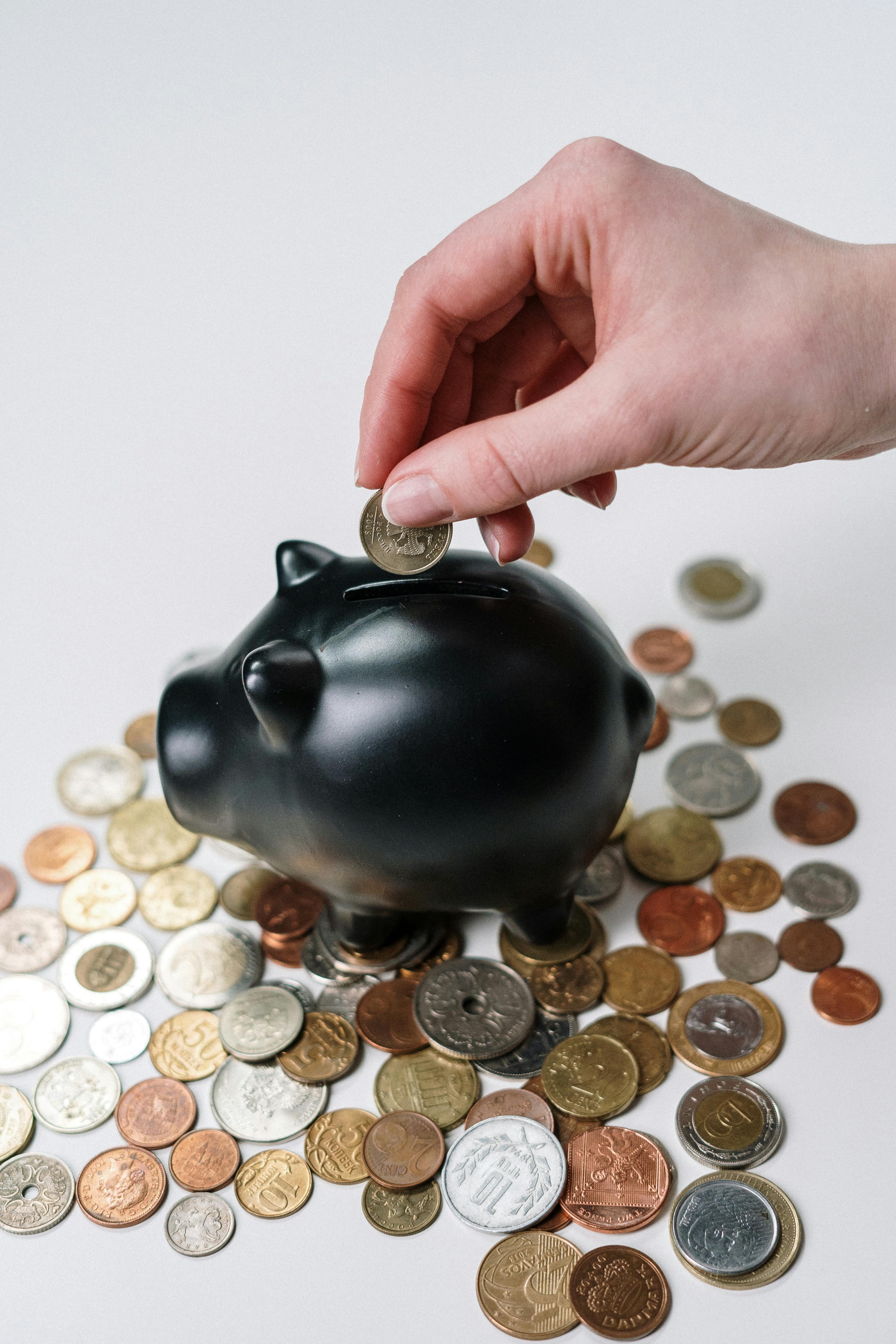 An illustrative photo of a person putting coin in a piggy bank