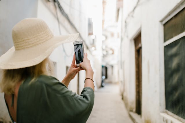 An illustrative photo of  woman capturing a photo of a building while standing in a narrow alley